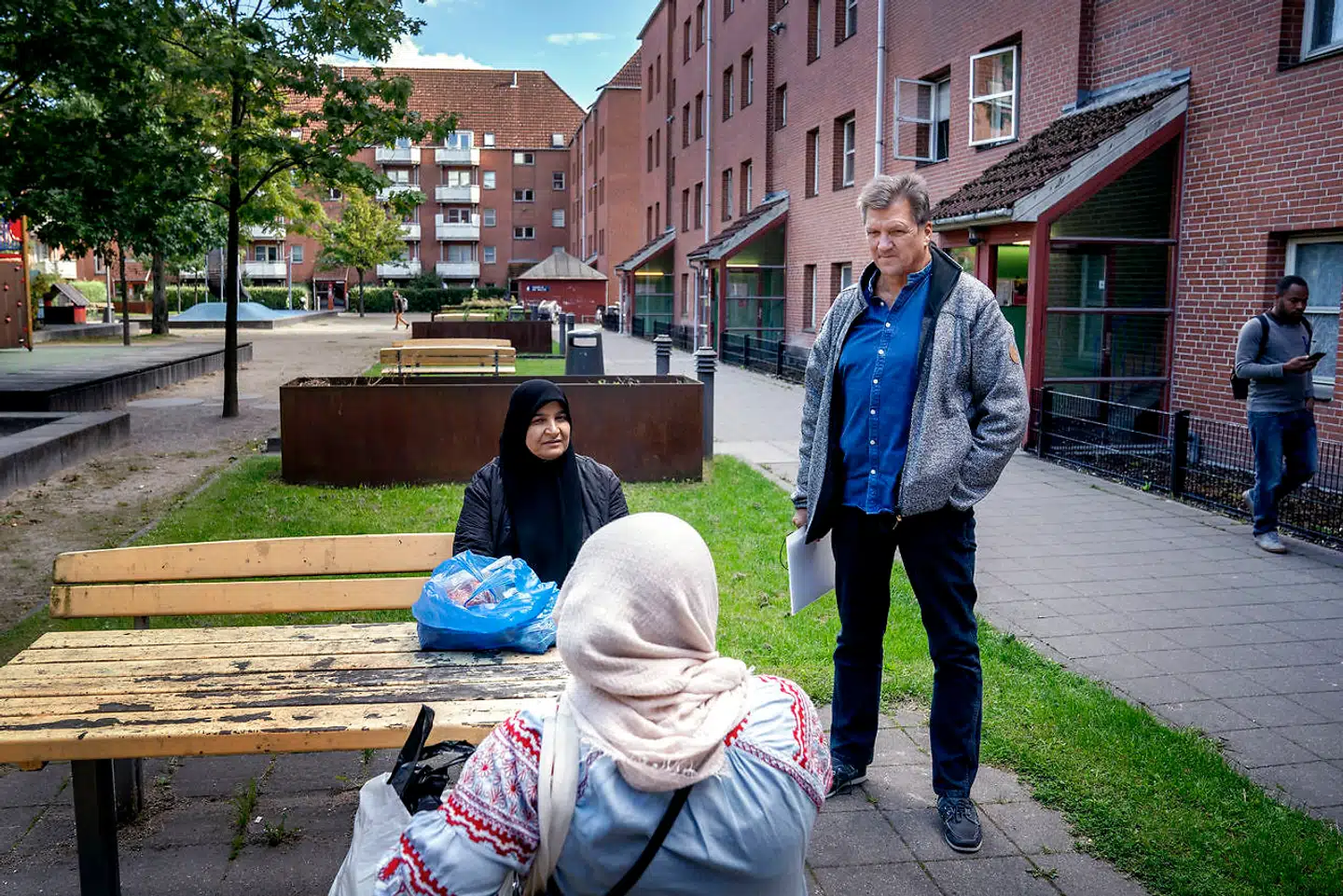 Beboerne hilser på Bo-Vitas tryghedskonsulent Søren Wiborg, da han er i boligselskabets afdeling i Mjølnerparken for at aflevere nogle breve. To kvinder spørger ind til situationen med fraflytning fra området, der er sat i værk som følge af ghettoplanen, hvor 60 procent af boligerne skal sælges.