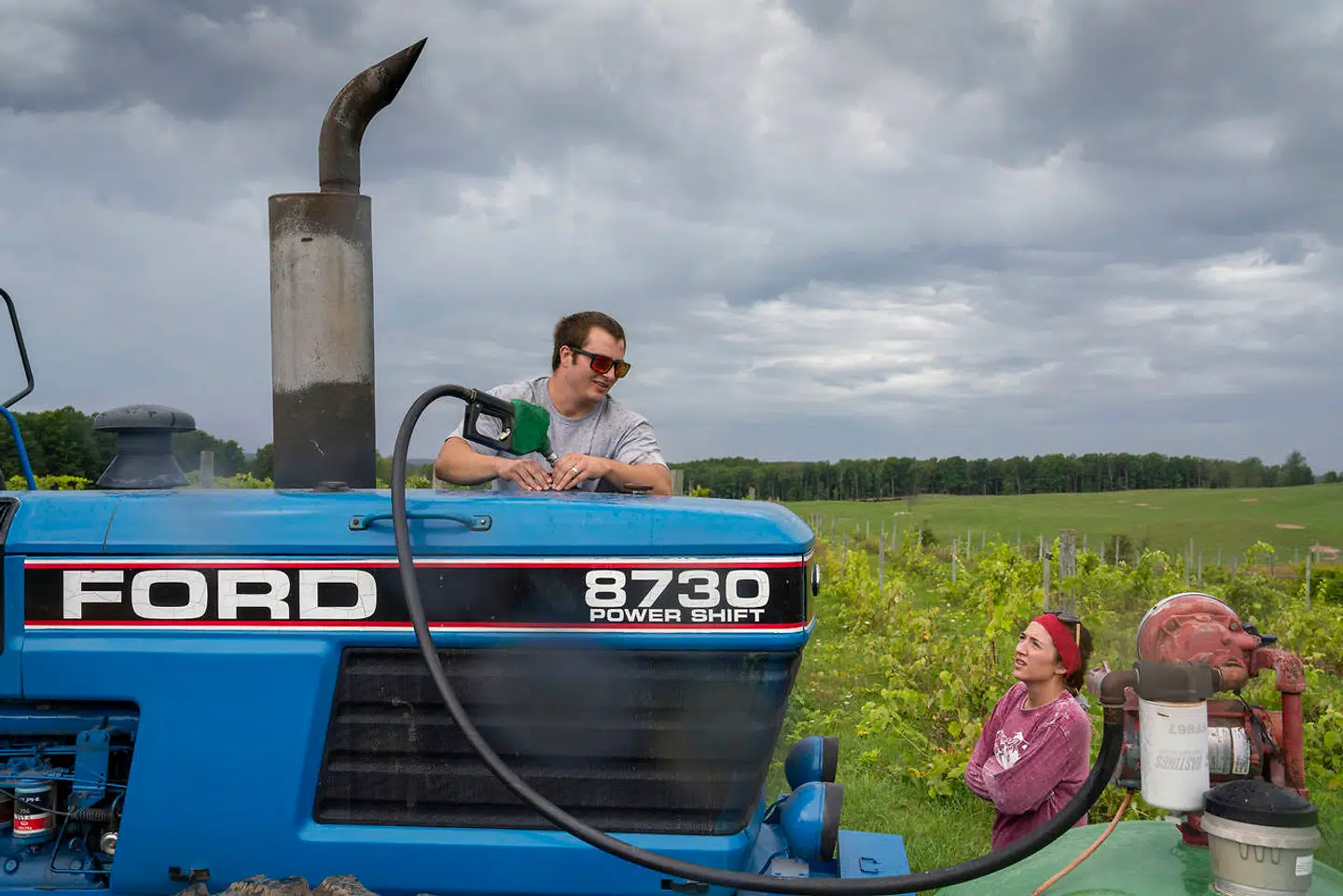 Carl Brasseurs søn, Kyle på 25 år, tanker gårdens store Ford-traktor op, mens Carls Brasseurs datter ser til.