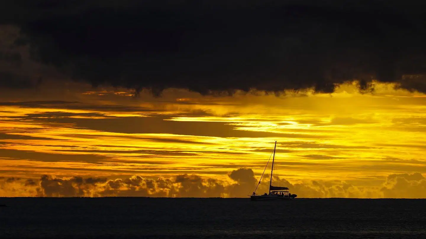 En båd sejler i Det Indiske Ocean under solnedgang ved Pereybere-stranden i det nordlige Mauritius. Opstandelsen over korruptionssagen har været stor og har kostet vicepremierministeren jobbet i landet.