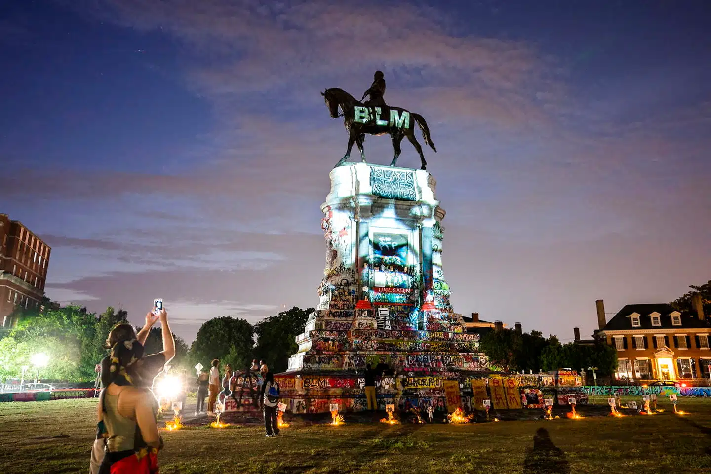 Et billede af den politidræbte sorte mand George Floyd blæst op på det 12 ton tunge monument for sydstatsgeneralen Robert E. Lee på Monument Avenue i Richmond, Virginia. »BLM« står der på selve statuen for bevægelsen Black Lives Matter, der ser statuer af sydstatsgeneraler som udtryk for hvidt overherredømme, og derfor kæmper for at få dem fjernet, hvilket nu sker i stor stil. Næste bølge kan omfatte præsidenter. EPA/JIM LO SCALZO