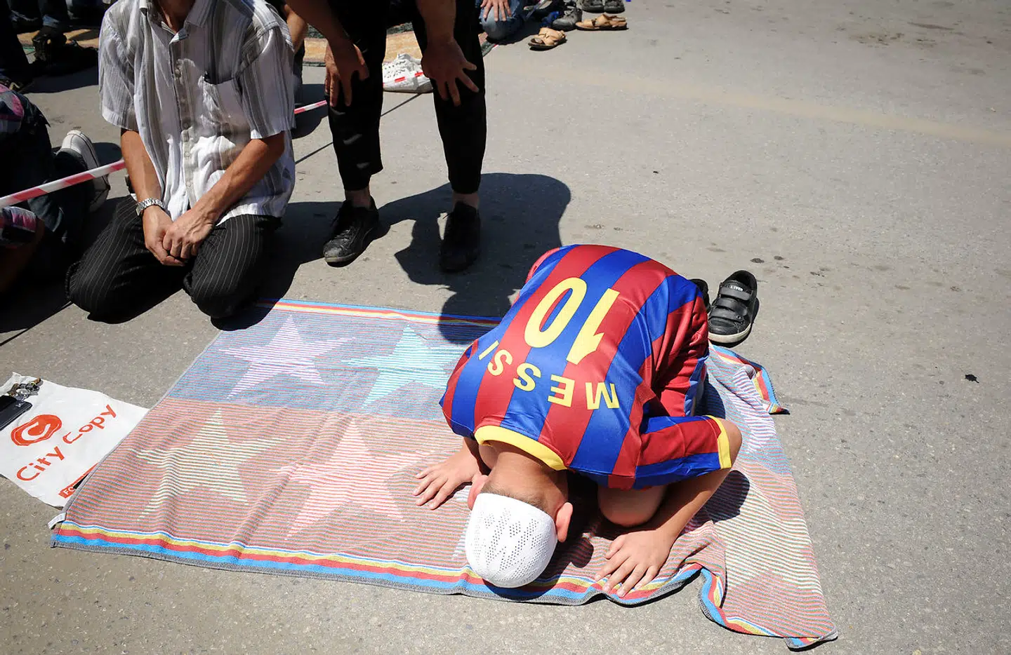 Forgudelsen af Lionel Messi er global. Her beder en dreng fra Kosovo uden for en moské i Pristina iført FC Barcelona-stjernens trøje.