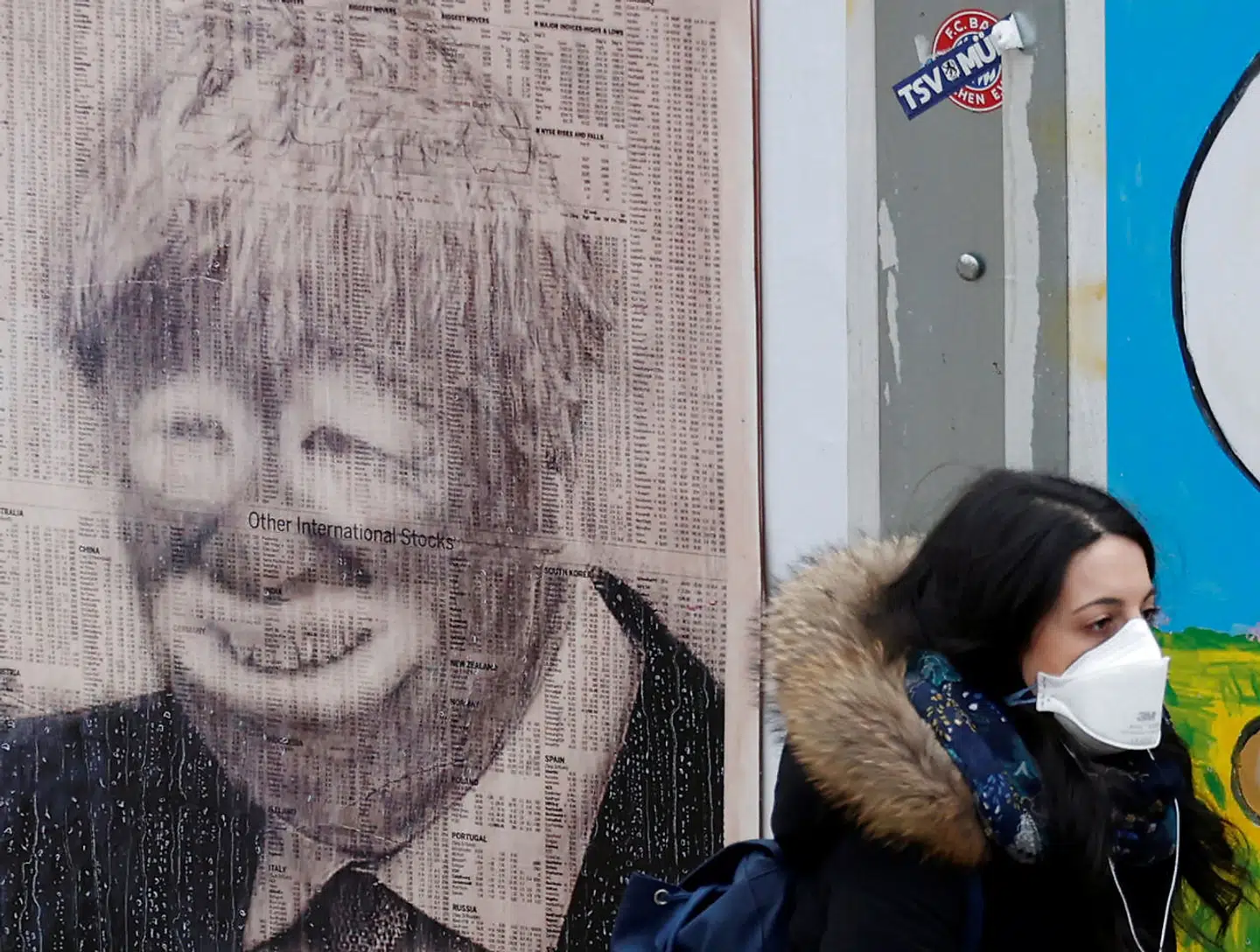 En kvinde med mundbind går forbi en vægtegning af Boris Johnson i Manchester. Den britiske coronaindsats udviklede sig til en katastrofe, fordi Boris Johnson fulgte den såkaldte nudge-teori i stedet for at lukke landet ned.