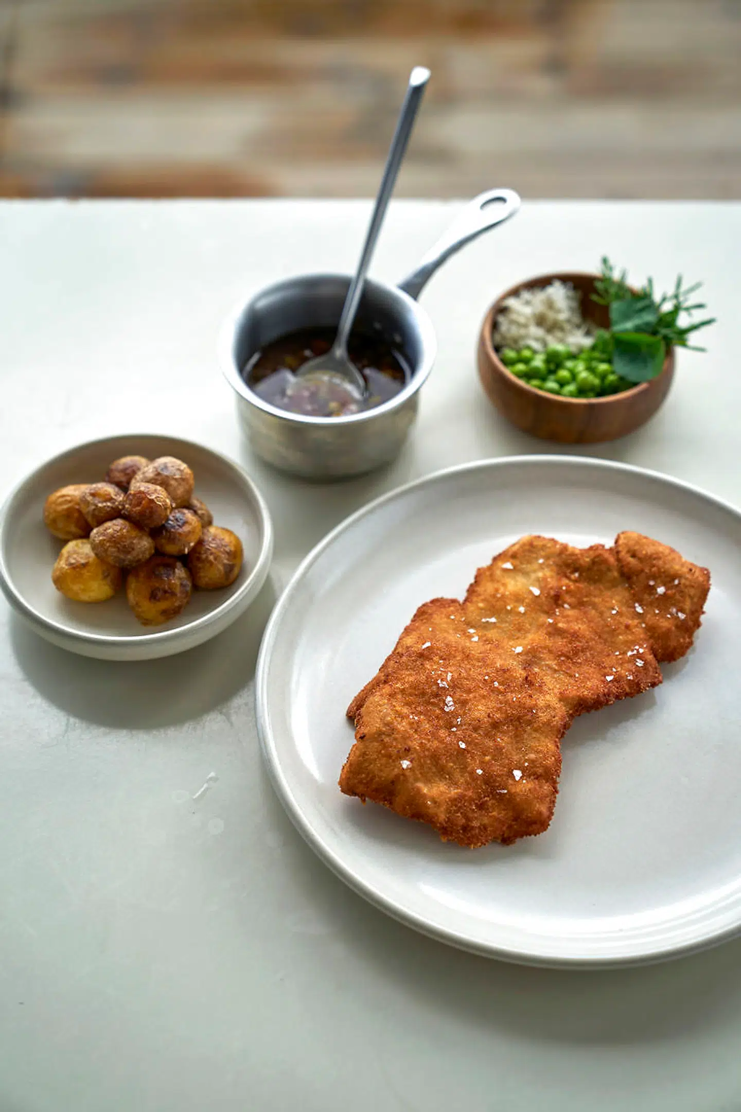 En ordentlig kleppert af en wienerschnitzel dobbeltpaneret og gyldent sprødstegt. Serveret med blidt stegte, nyopgravede Lammehavekartofler, brunet smør med kapers og ansjoser samt en garniture af nye ærter, grønne asparges og friskrevet peberrod.