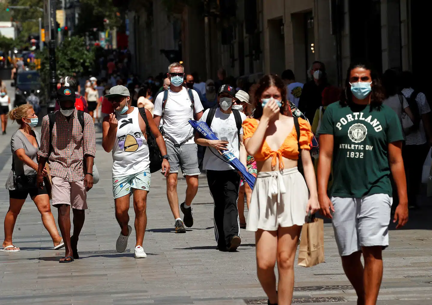 To »hagedaskere« (til venstre i billedet) spadserer ned ad en gade i det centrale Barcelona. Ikke alle spanierne bærer de obligatoriske masker på den mest effektive måde.