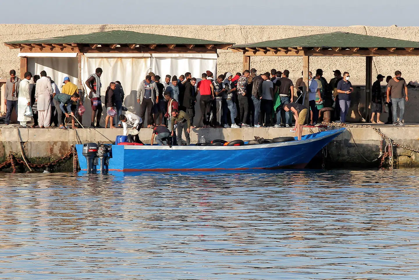 Migranterne hober sig op på øen Lampedusa, der ligger tæt på Tunesiens kyst. Herfra overføres de til Sicilien for at udstå karantæne på grund af coronapandemien, inden de overføres til permanente lejre. Det italienske modtagesystem har svært ved at følge med, efter tilstrømningen i juli er steget eksplosivt.