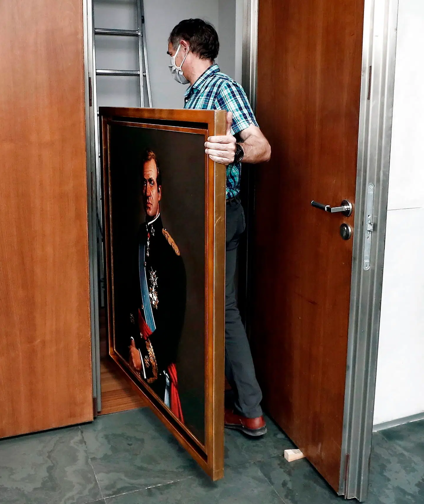 Et portræt af ekskong Juan Carlos fjernes fra det regionale parlaments plenumsal i Navarras hovedstad, Pamplona, efter afsløringen af hans angivelige økonomiske forbrydelser.