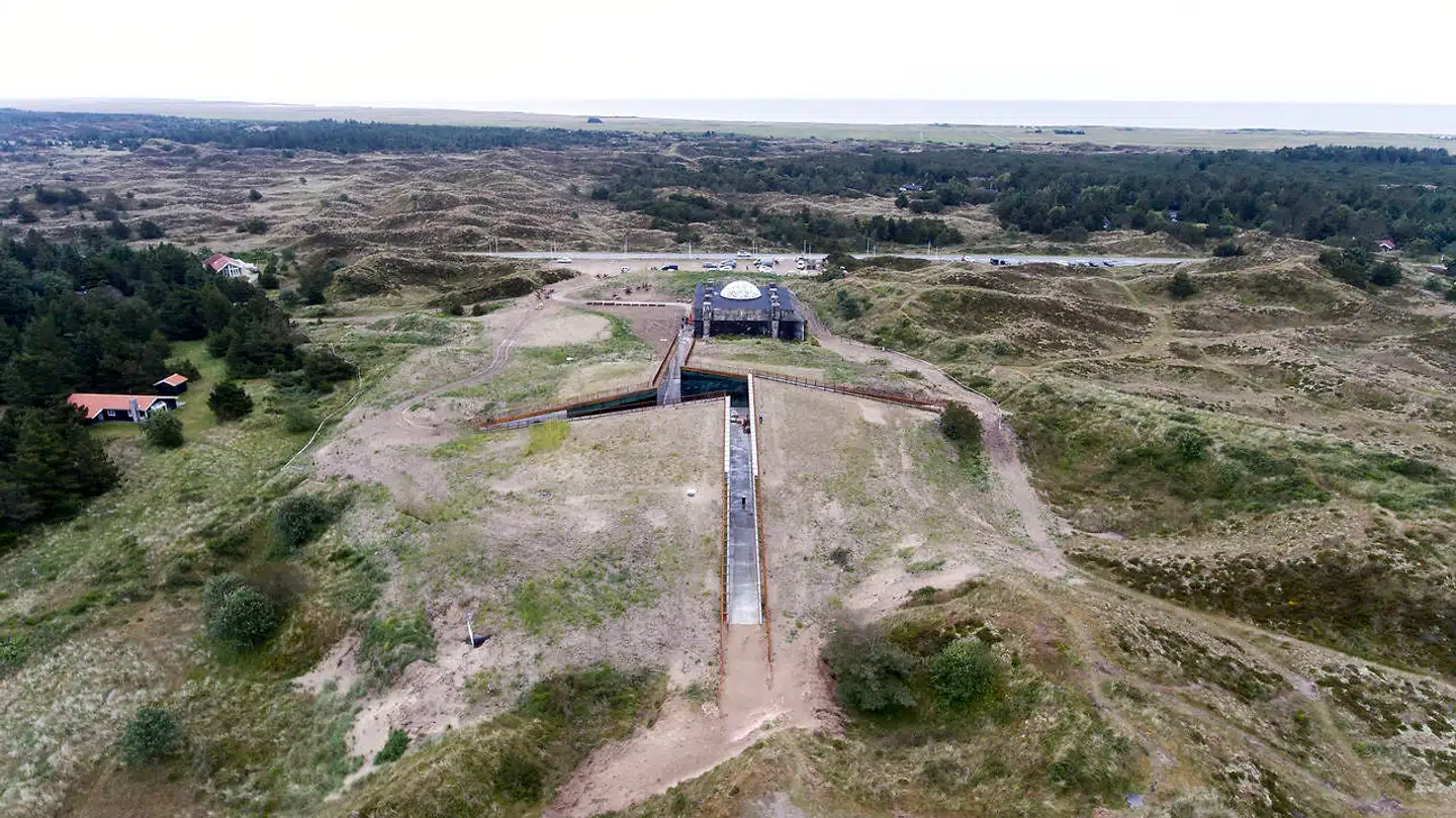Tirpitzmuseet ligger som en kunstig klit i landskabet. Hvis man er konceptuelt indstillet, kan man se et dekonstrueret hagekors i skårene, der fører ind til gården og billetsalget.