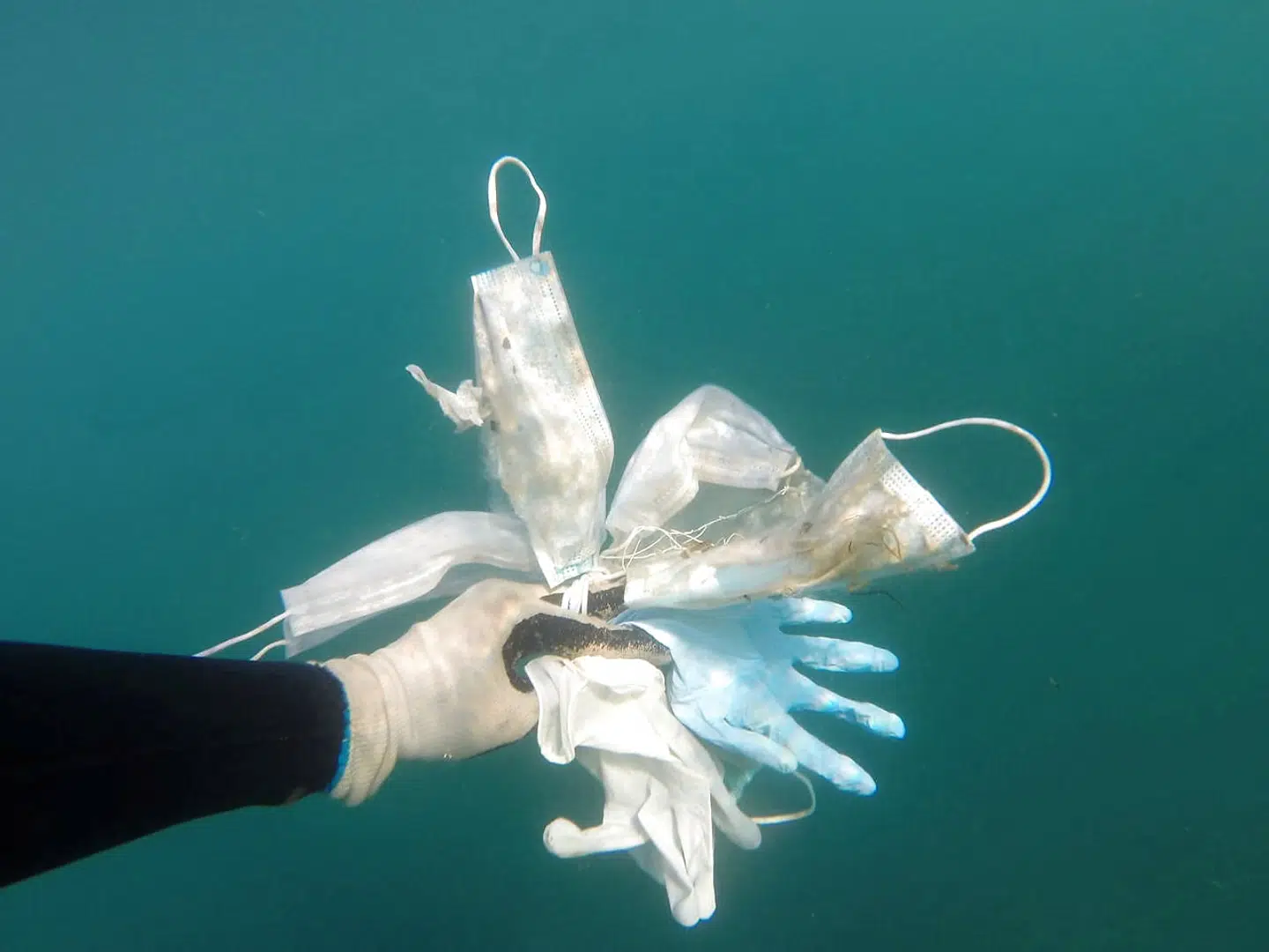 Gloves and protective face masks are held, amid the coronavirus disease (COVID-19) outbreak, in this picture taken by a sea clean-up volunteer diver in the Mediterranea sea in May 2020. Laurent Lombard/Operation Mer Propre via REUTERS THIS IMAGE HAS BEEN SUPPLIED BY A THIRD PARTY. MANDATORY CREDIT.NO RESALES.NO ARCHIVES.