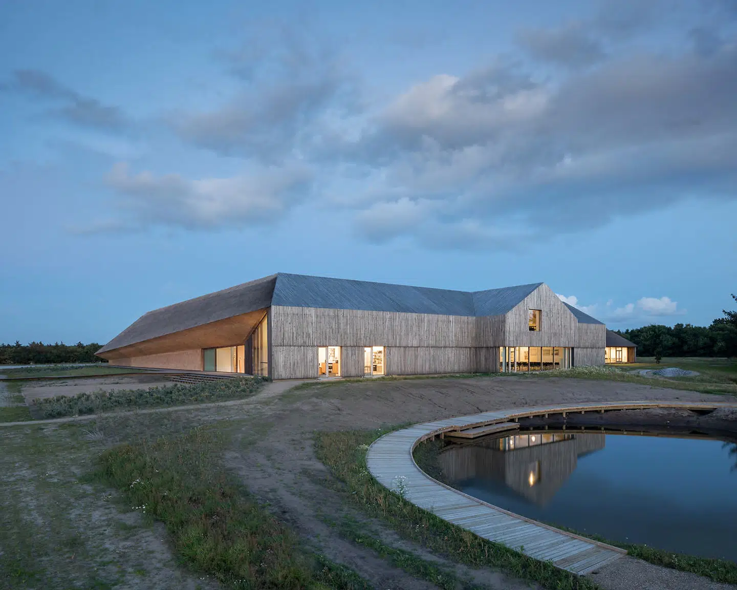 Den vestlige længe har et indbygget gavlmotiv og er beklædt med tynde stave i robinietræ.