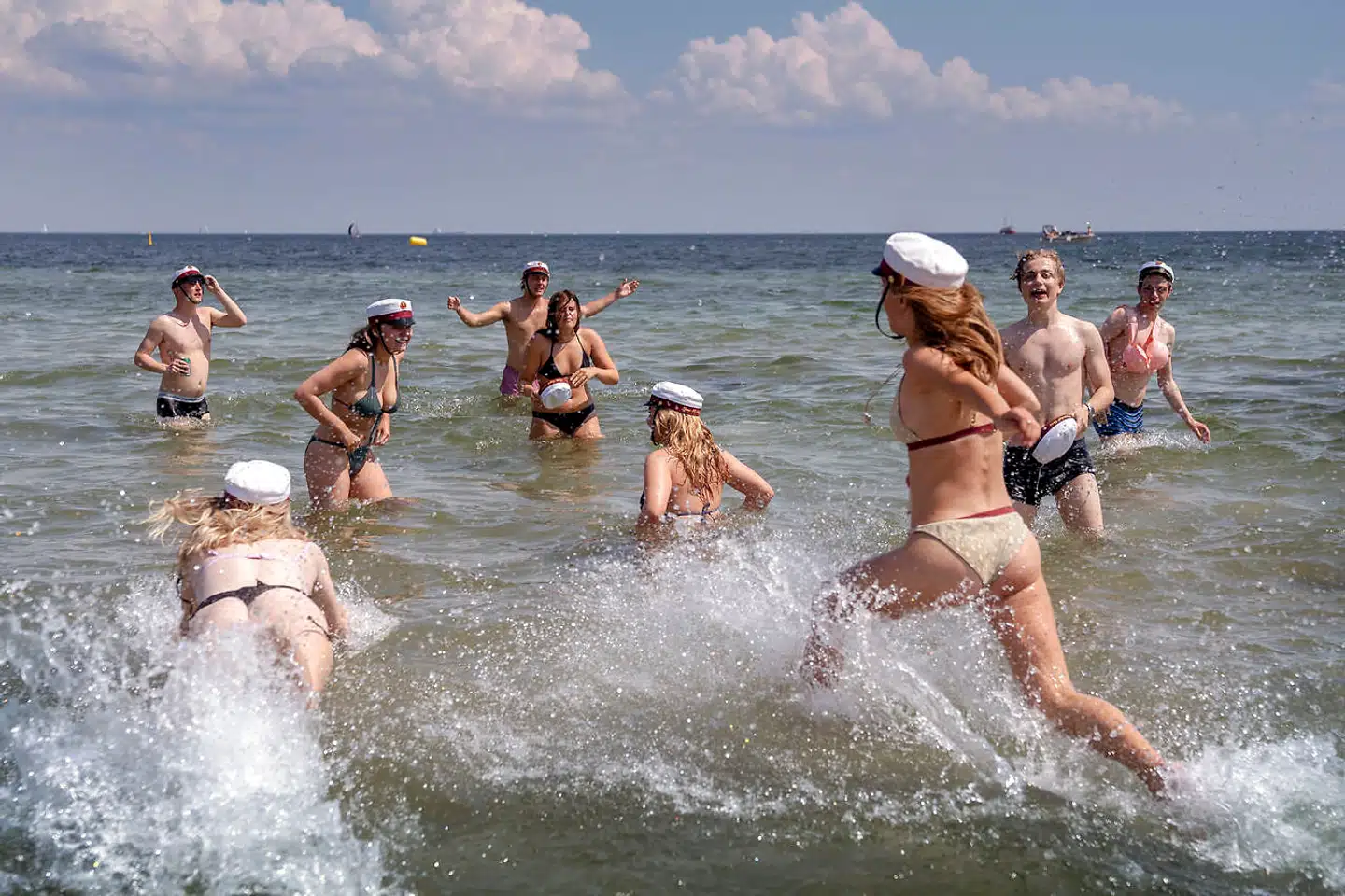 Et hold studenter fra Øregård Gymnasium hopper i havet på Hellerup Strand i de varme dage i juni. Der har været stor bekymring, om for eksempel studenterfesterne ville sprede smitte på ny, men ifølge smittestatistikken er det ikke sket.