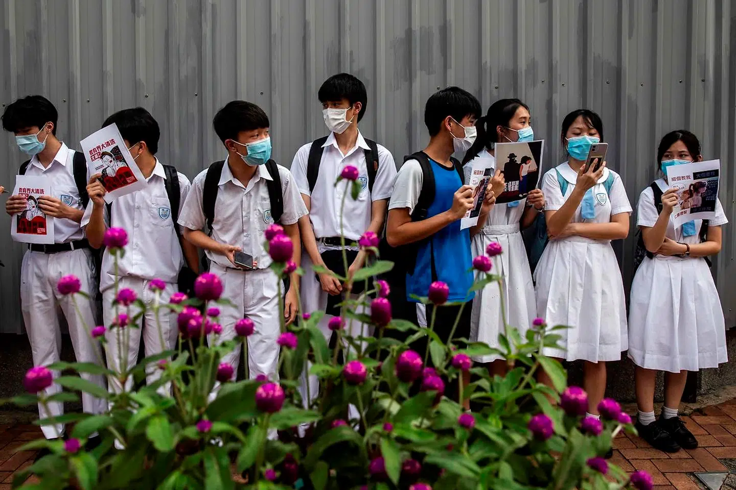 Skoleelever deltager i en demonstration nær deres skole i Hongkong. Fremover risikerer eleverne, at myndighederne slår til, såfremt de taler politik.