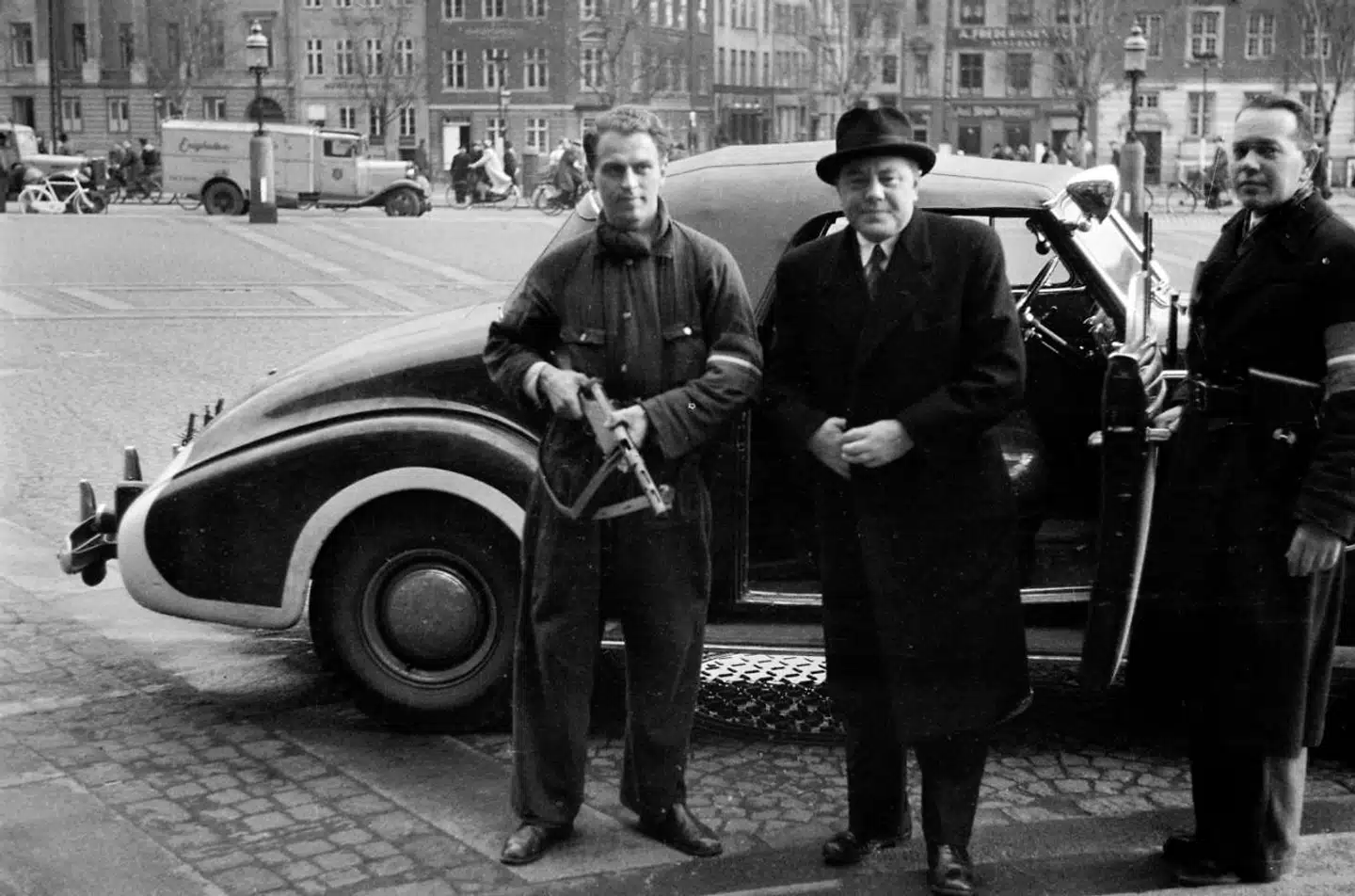 Den kommende arbejds- og socialminister Hans Hedtoft ankommer sammen med et par bevæbnede frihedskæmpere til Christiansborg 1945. Hans Hedtoft skulle som statsminister (S) komme til at spille en rolle under Den Kolde Krig.