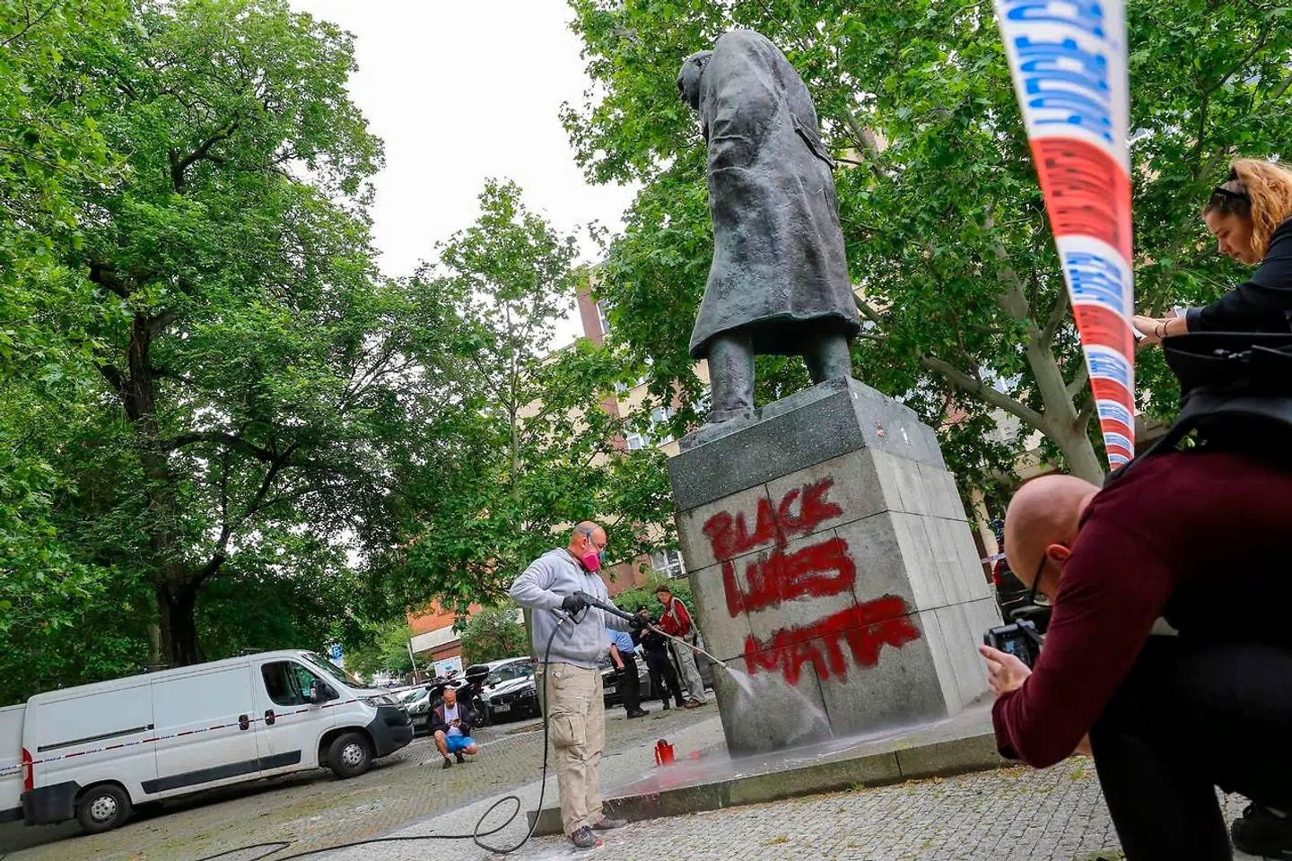 På billedet her er en person ved at fjerne graffiti fra en statue af Winston Churchill i Prag. I flere lande er lignende statuer blevet fjernet eller overhældt med maling.