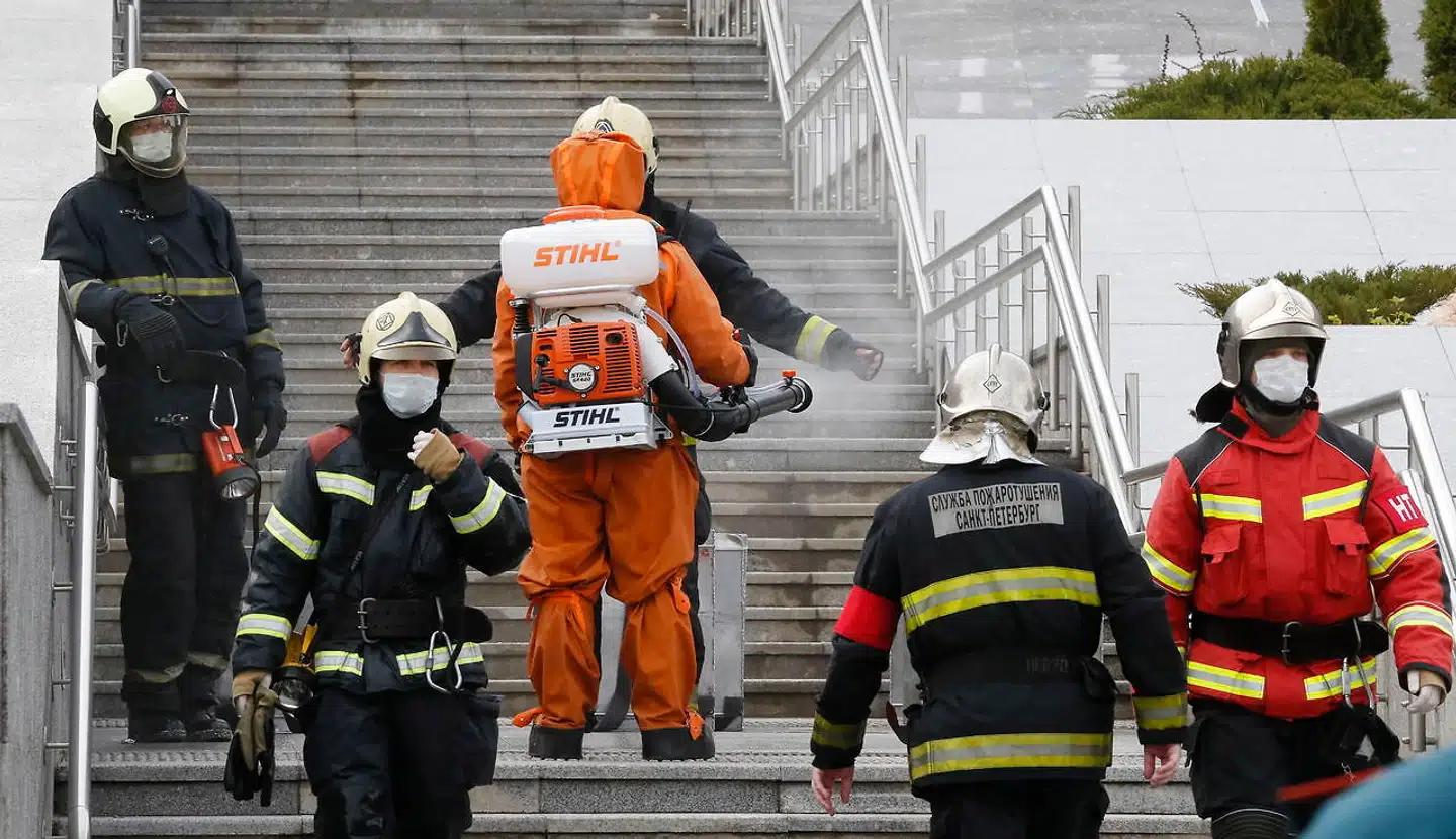 Foran Sankt Georgs Hospital i Sankt Petersborg sprøjter en hjælpearbejder brandfolk med desinficerende væsker. En brand på hospitales coronaafsnit kostede tirsdag morgen fem patienter livet.