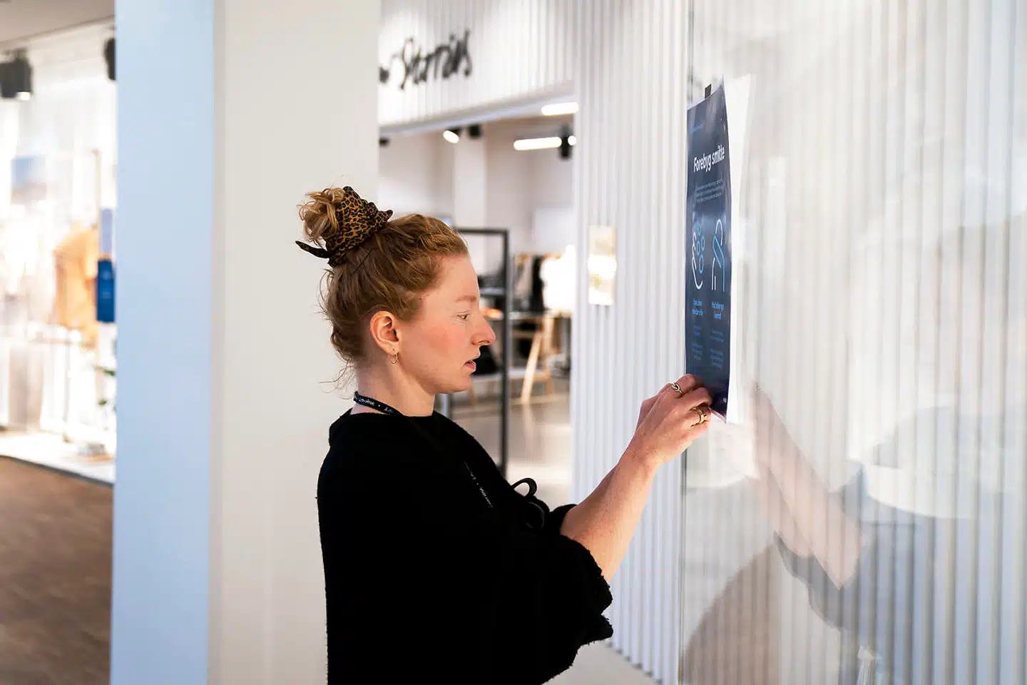 Sarah Soland sætter corona-information op ved & Other Stories i Lyngby Storcenter.