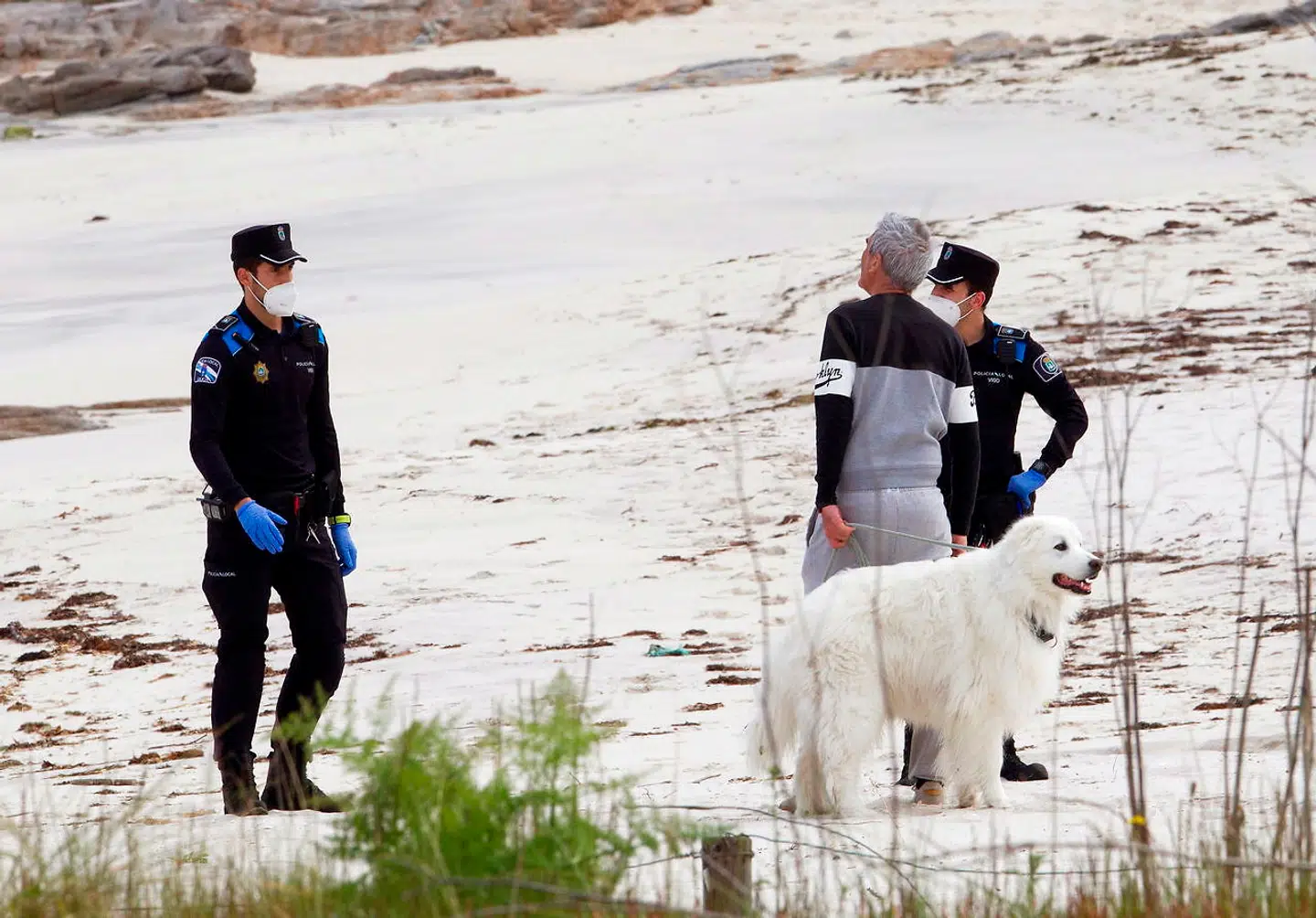 Betjente giver en mand besked om, at det er forbudt at lufte hunde og i øvrigt opholde sig på en ellers øde strand nær den nordvestspanske by Vigo.
