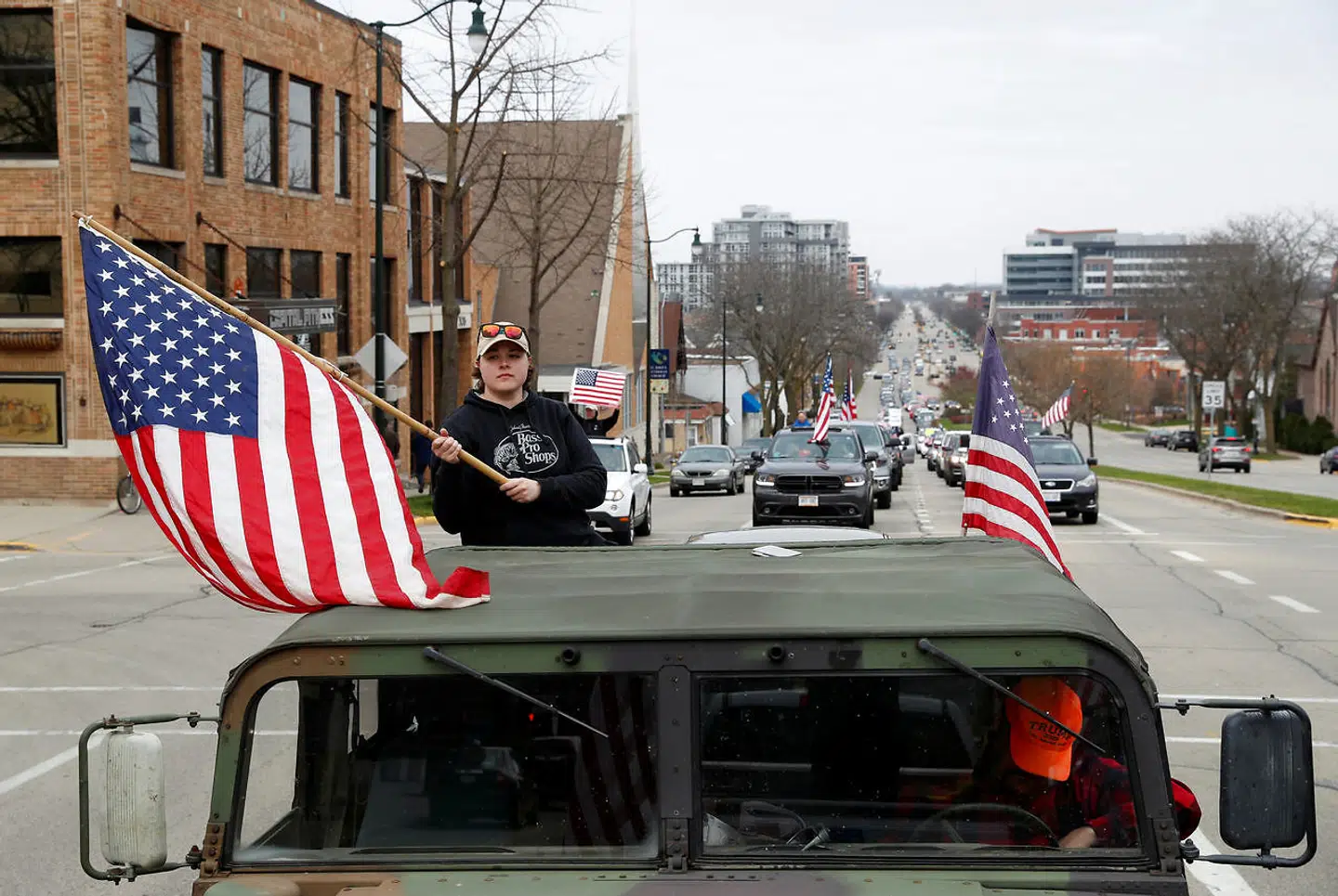 En ung kvinde flager med det amerikansk flag fra en Humwee i protest mod forlængelsen af bliv hjemme-påbuddet i Wisconsin.