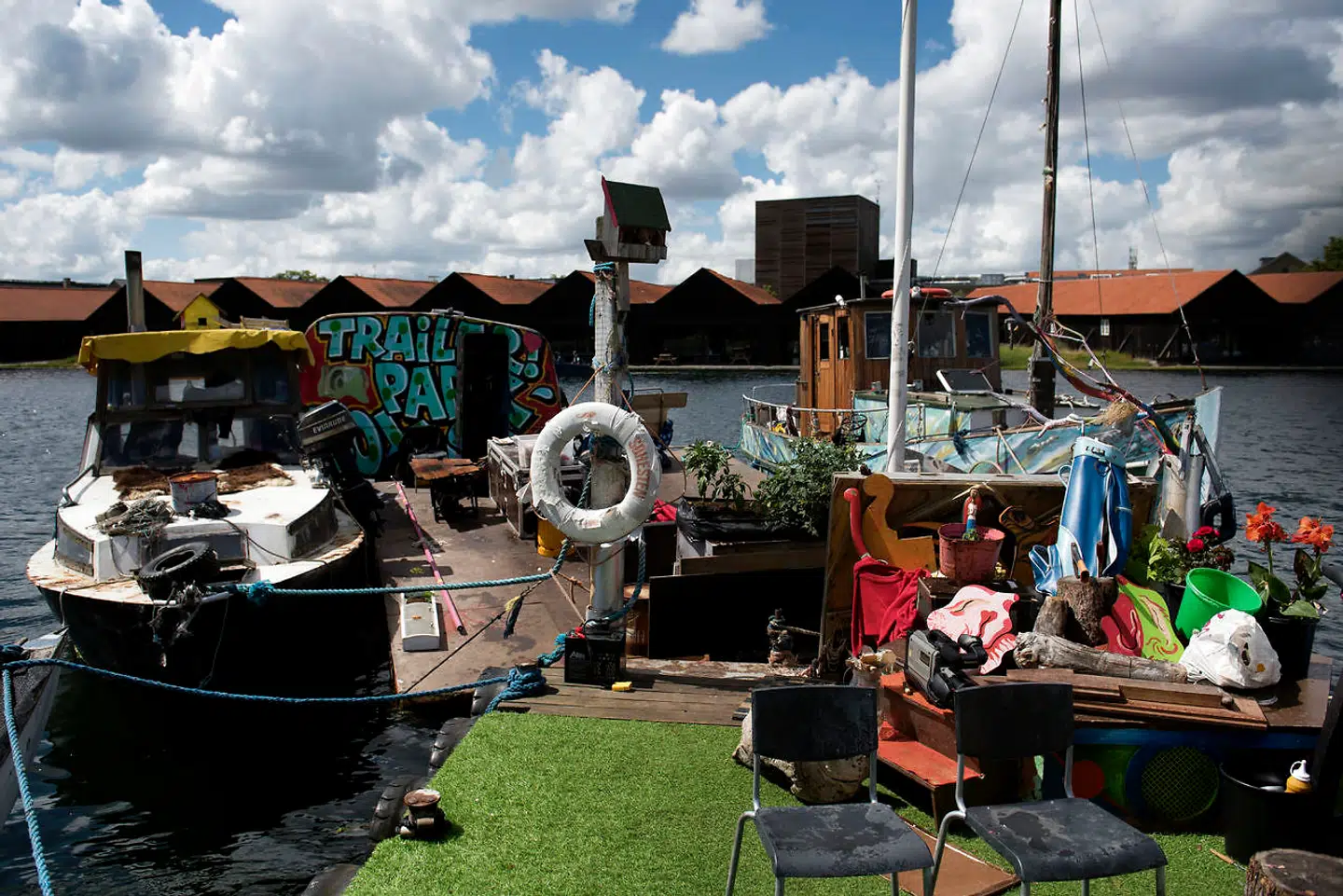 På Æseløen ligger fire fartøjer og et gæstehus blandt bamser, blomster og planter. Beboerne er tre kærestepar, som deler det meste fra værktøj til mad. »Sidste år var det ren Roskilde Festival, men nu har de unge mænd fået kærester, og der er kommet totalt ro på. De går og vander blomster og alt muligt,« fortæller Esben Banke.