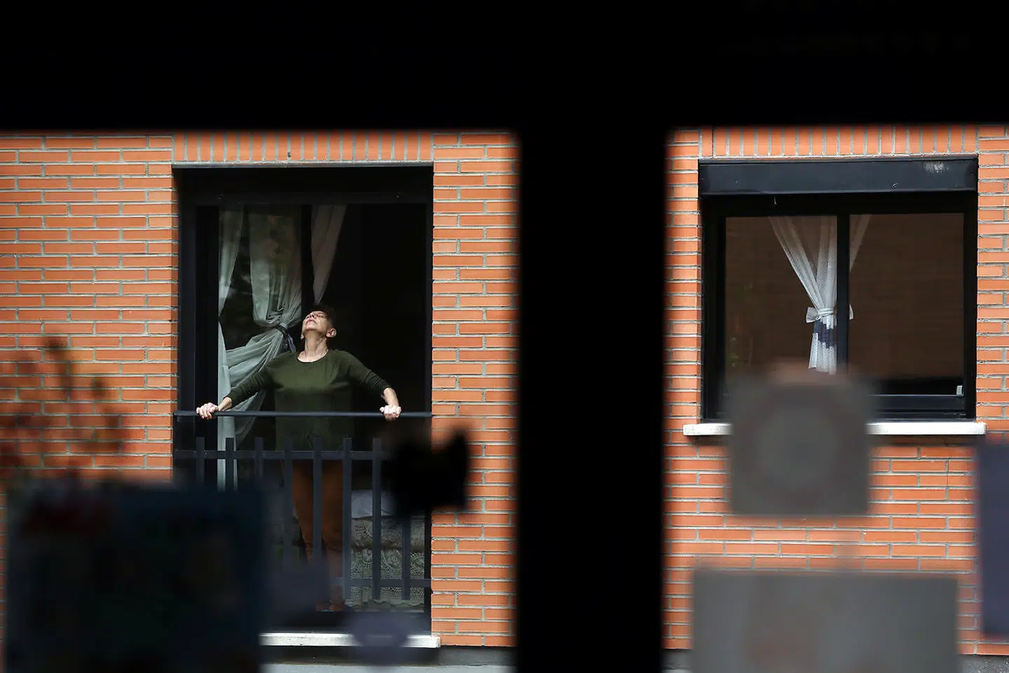 En kvinde laver strækøvelser og trækker samtidig frisk luft på sin altan i den spanske hovedstad, Madrid.