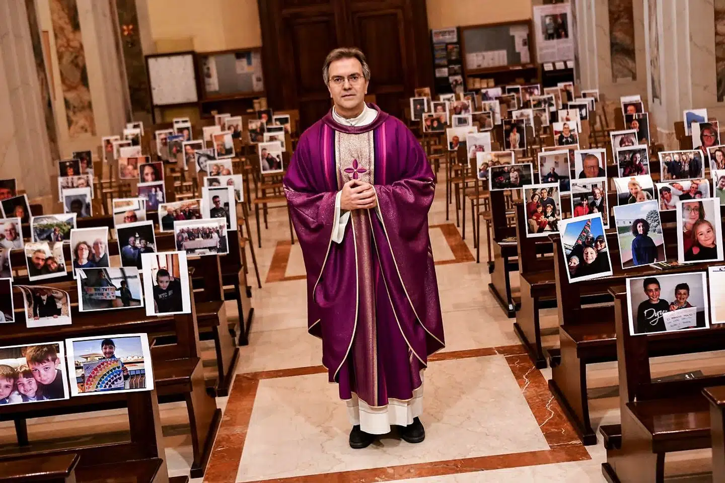 TOPSHOT - Don Giuseppe Corbari, parson of the Church of Robbiano, poses between selfie photographs sent in by his congregation members and glued to empty pews, before celebrating Sunday mass in Giussano on March 22, 2020. - Italian Prime Minister Giuseppe Conte on March 21 ordered all non-essential companies and factories to close nationwide to stem a coronavirus pandemic that has killed 4, 825 people in the country in a month. "The decision taken by the government is to close down all productive activity throughout the territory that is not strictly necessary, crucial, indispensable, to guarantee us essential goods and services, " Conte said in a late-night TV address (Photo by Piero CRUCIATTI / AFP)
