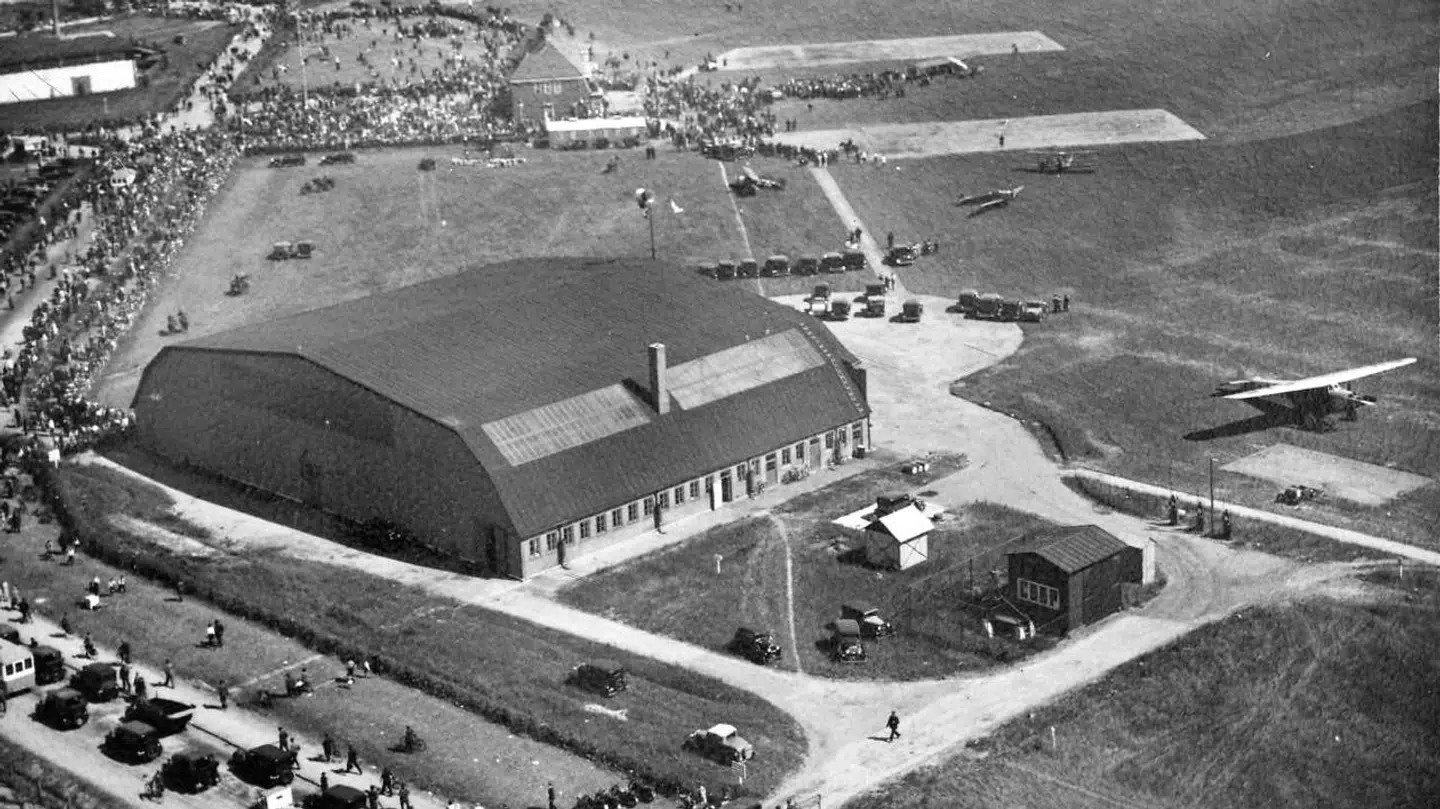 Kastrup lufthavn, som den så ud 1925. I forgrunden ses hangaren og bagved administrationsbygningen og det berømte »krudthus«. Dengang bare en flyveplads. I dag en vigtig livsnerve for hele Danmark.