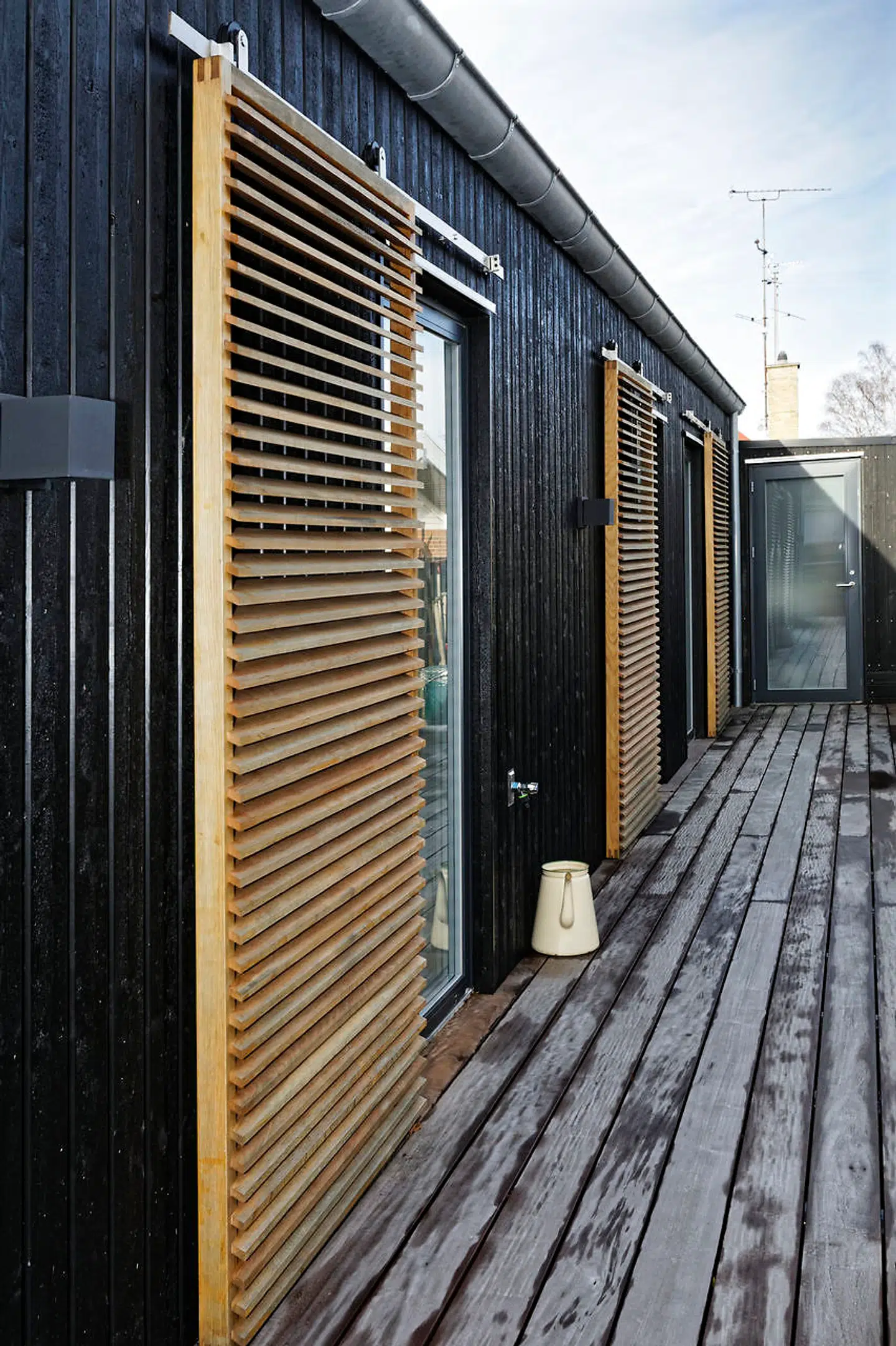 Husets facader er beklædt med sortmalet gran, har egeskodder, vinduer af massiv bøg og hårdttræsdæk hele vejen rundt om huset og med »stationer« at sidde på flere steder.