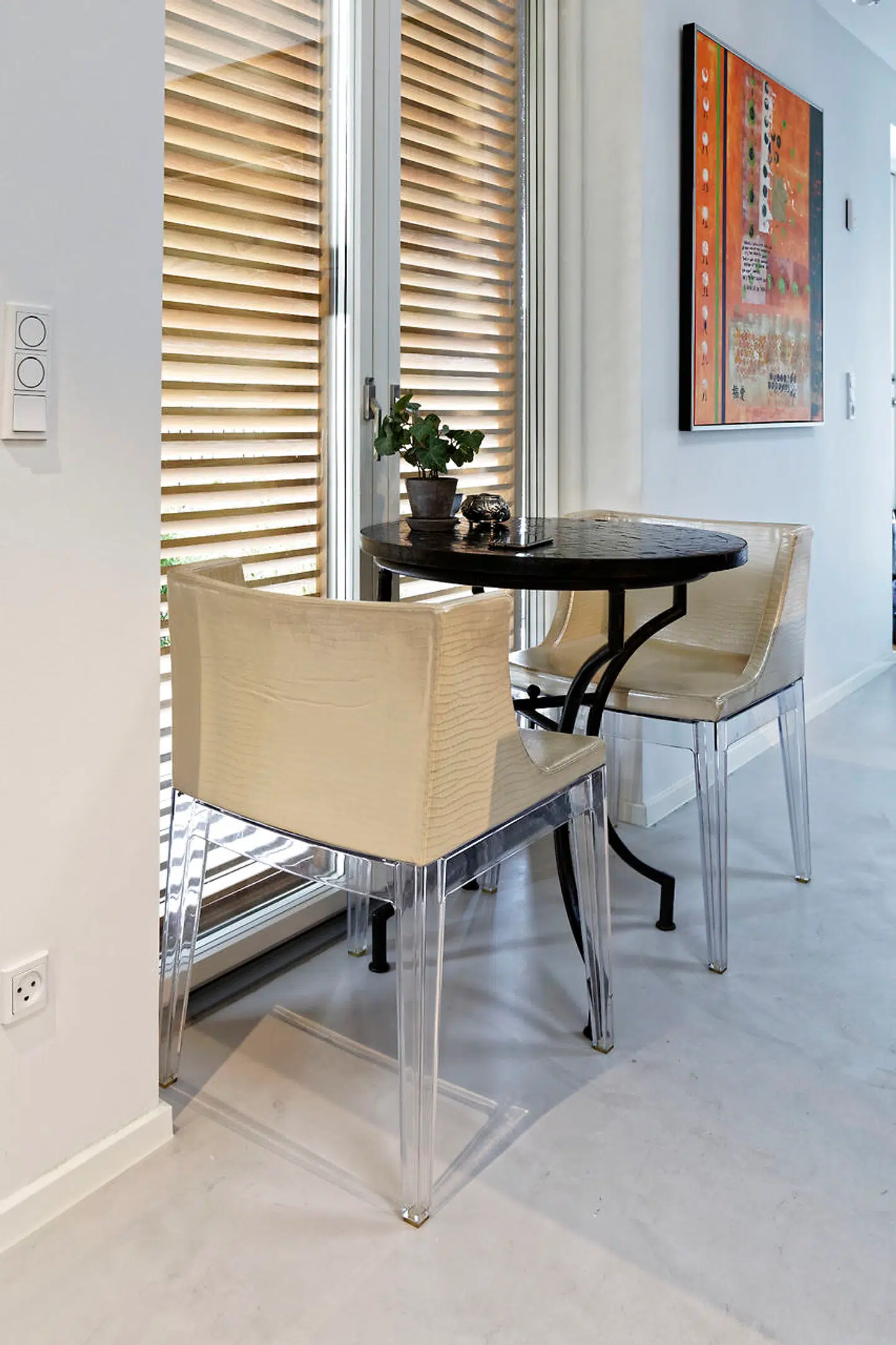 Et cafébord med Philippe Starck-stole i kunstskind står ved køkkenets store vindue med udendørs egeskodder, som rulles til og fra efter behov.