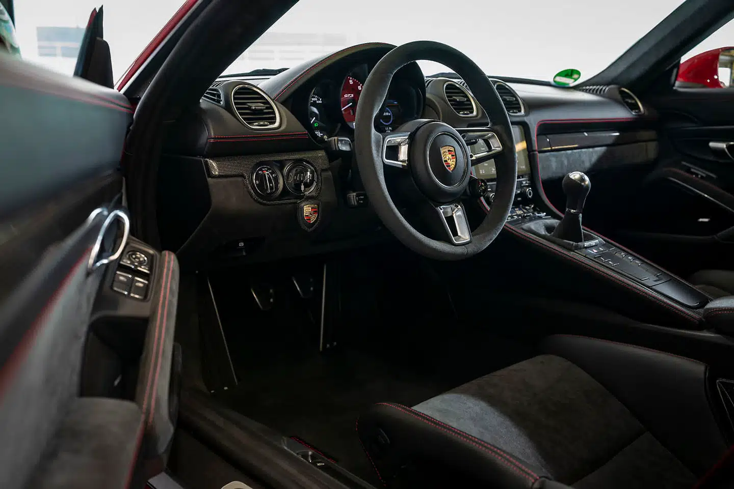 Kabinen er svøbt i alcantara og røde syninger. Porsche 718 Cayman GTS har masser af kompromisløs racerbaneattitude, den er lavere, hurtigere og mere direkte end Cayman S, og den har i den grad forstået rollen som GTS.