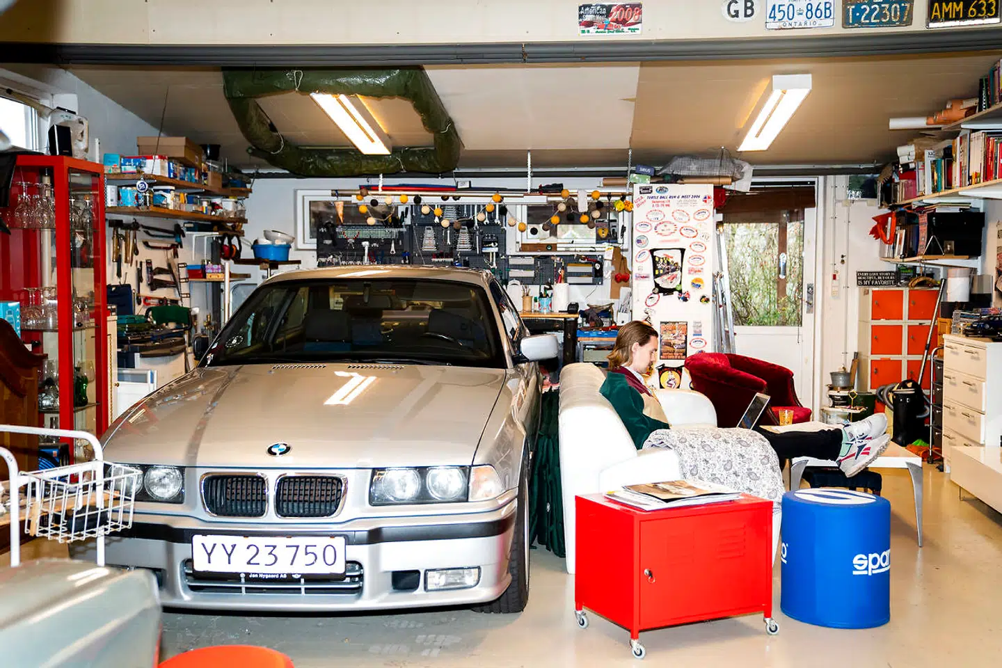 BMWen holder under dækken om vinteren parkeret bag en lyseblå lædersofa i garagen/slyngelstuen.