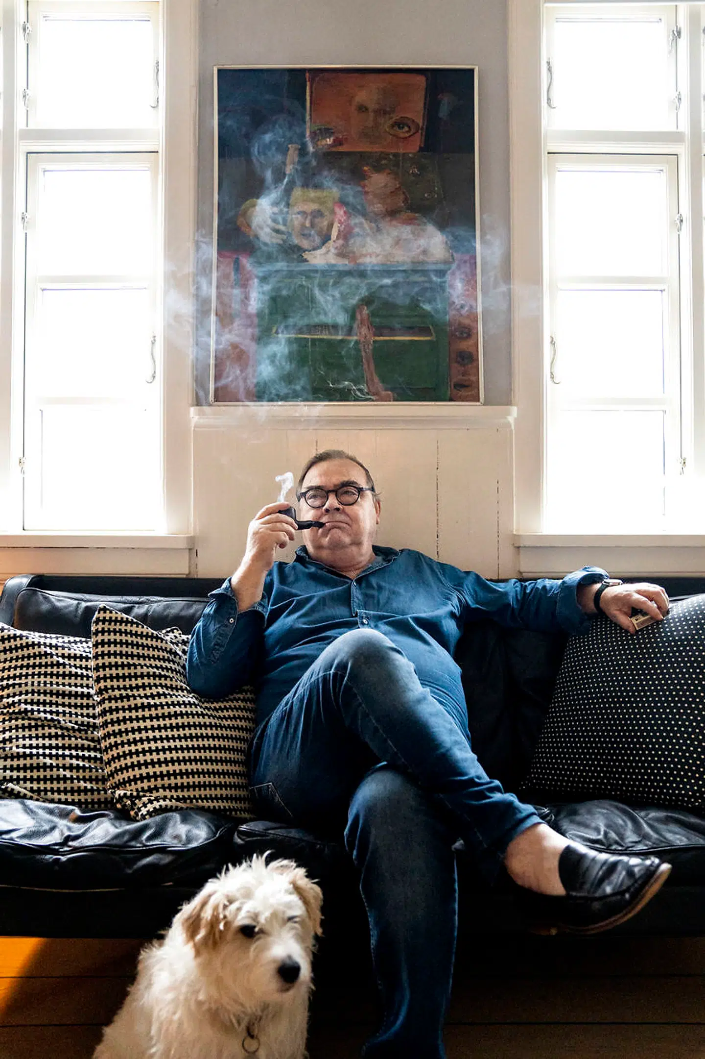 Henning Jacobsen sidder under sit favoritmaleri af Hans Christian Rylander med hunden Liva ved sin side.
