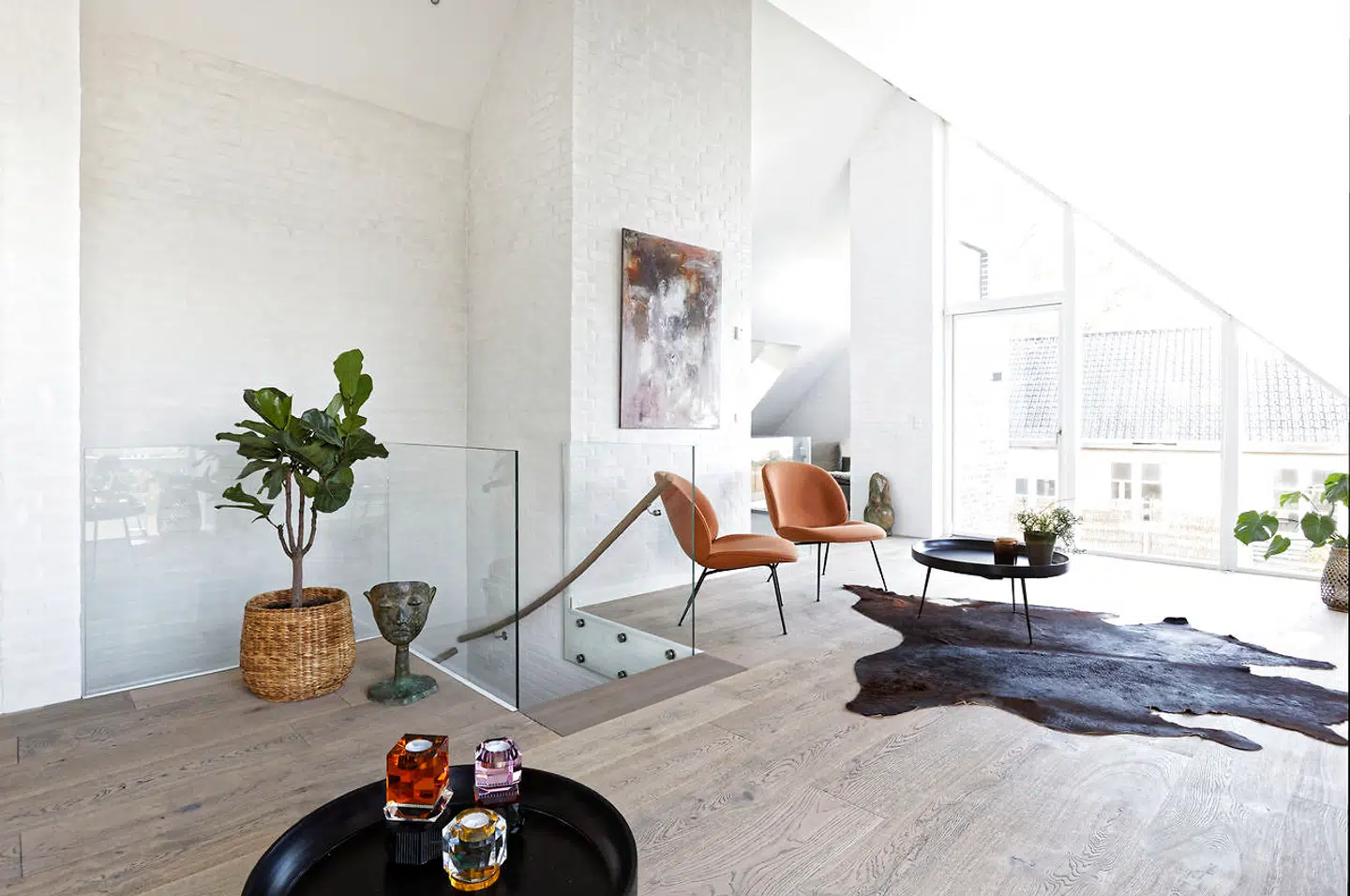 Flere malerier udskiftes jævnligt, når de bliver solgt. Her ses pladsen med koskind på det tobaksgrå plankegulv fra Haro, loungestole fra Gubi og bord fra Mater.