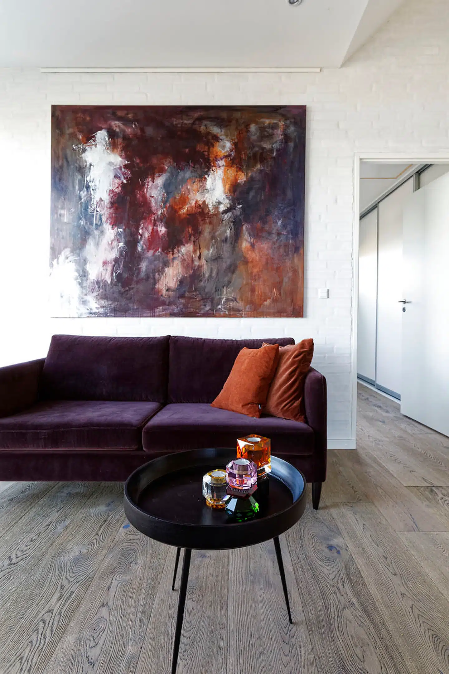 Den blommefarvede veloursofa er fra BoConcept. Den matcher farver i Filica Lysfalks maleri. Bordet er fra Mater og lysestagerne fra Reflection Copenhagen.