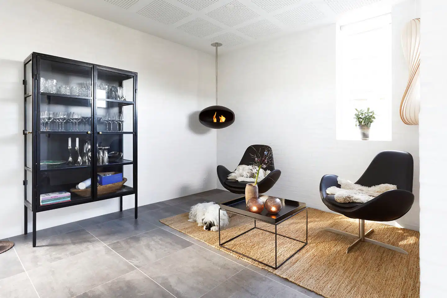 I et hjørne af køkkenet findes et loungeområde med Cocoon-biopejs, sisaltæppe fra Ilva, sort vitrineskab fra Ilva, Tom Rossau-birketræslampe og bakkebord fra HAY.