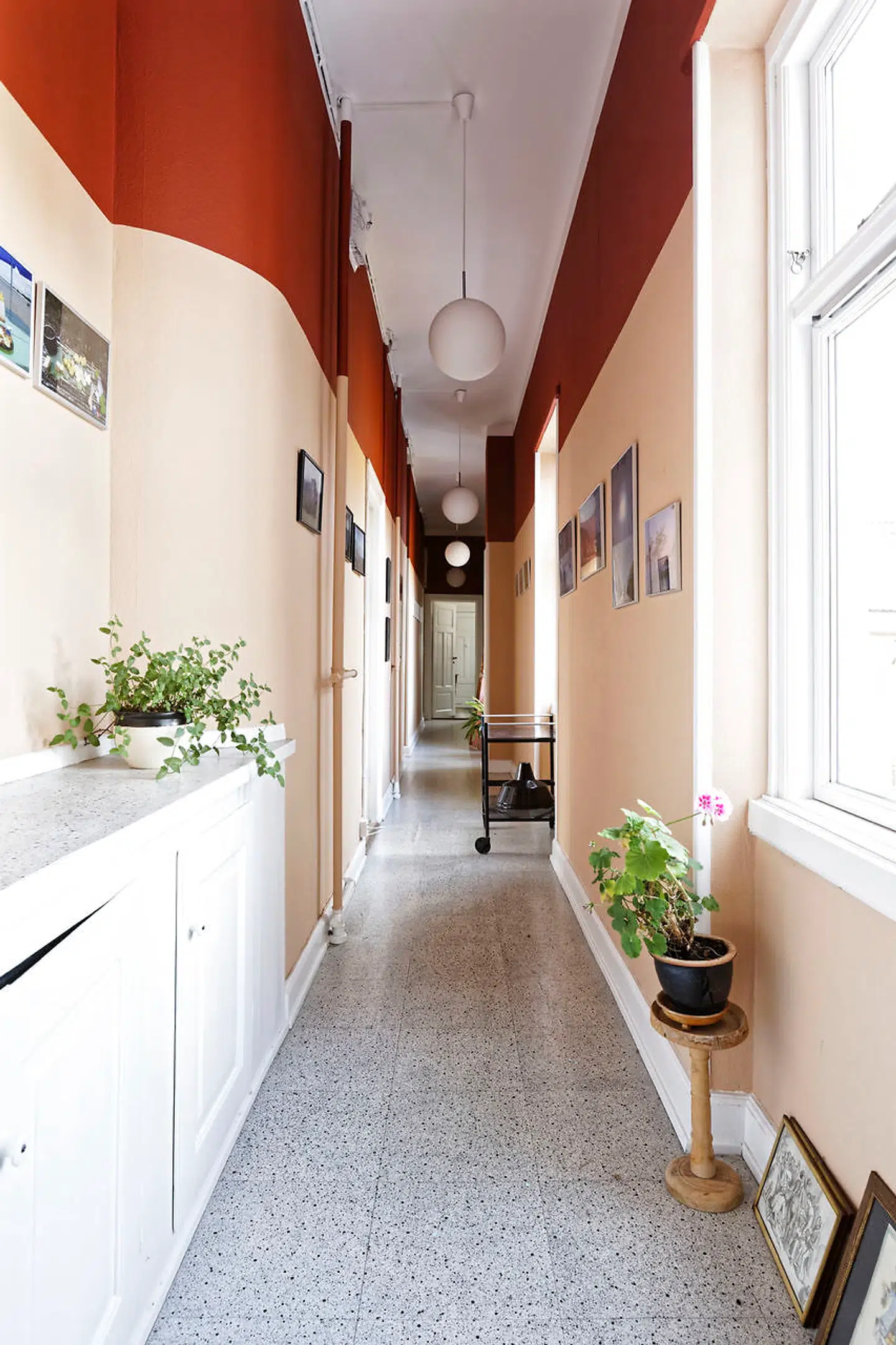 Den 15 meter lange serveringsgang er malet lys fersken og rust. På væggen hænger fotos fra rejser, blandt andet morgenmadsbilleder fra Sydamerika.