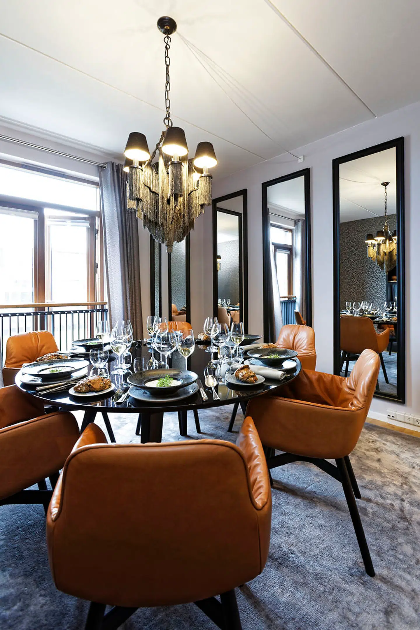 Spisebordsstole skal være behagelige. Disse er nærmest lænestole polstret med cognacfarvet læder. Bordet er custommade af Boelskifte Interiør & Design. De fire høje spejle giver rummet volumen og stemning.