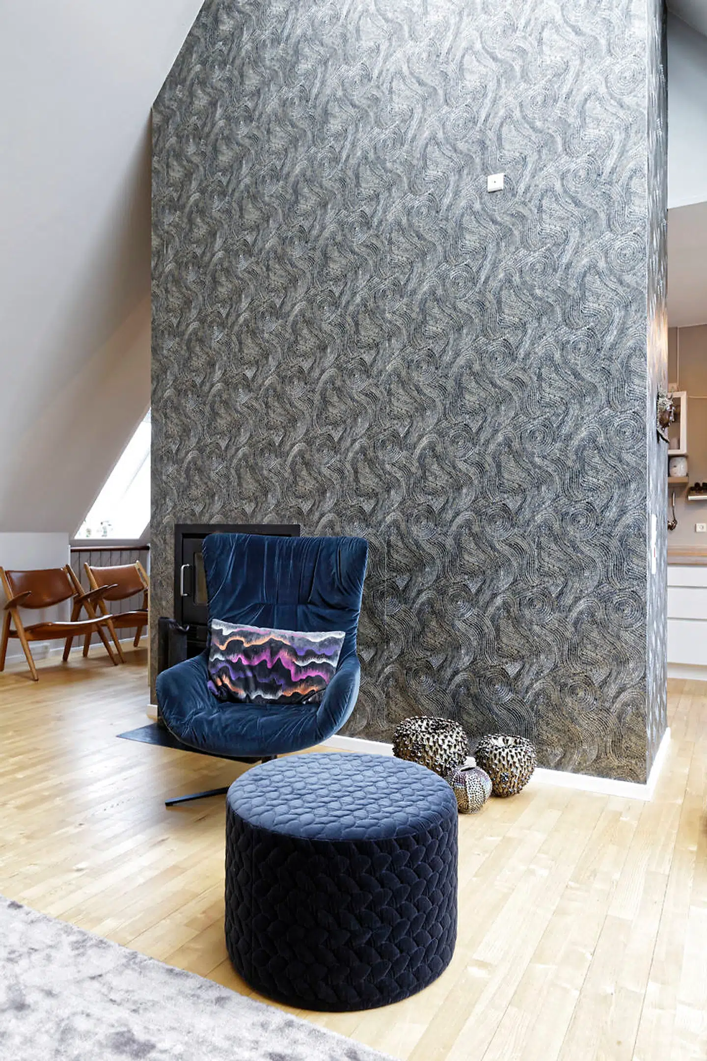 Delvæggen, som afgrænser køkken og stue, er tapetseret med mosaiktapet fra Zoffany. De velourbeklædte pufs er fra Boelskifte Interiør & Design.