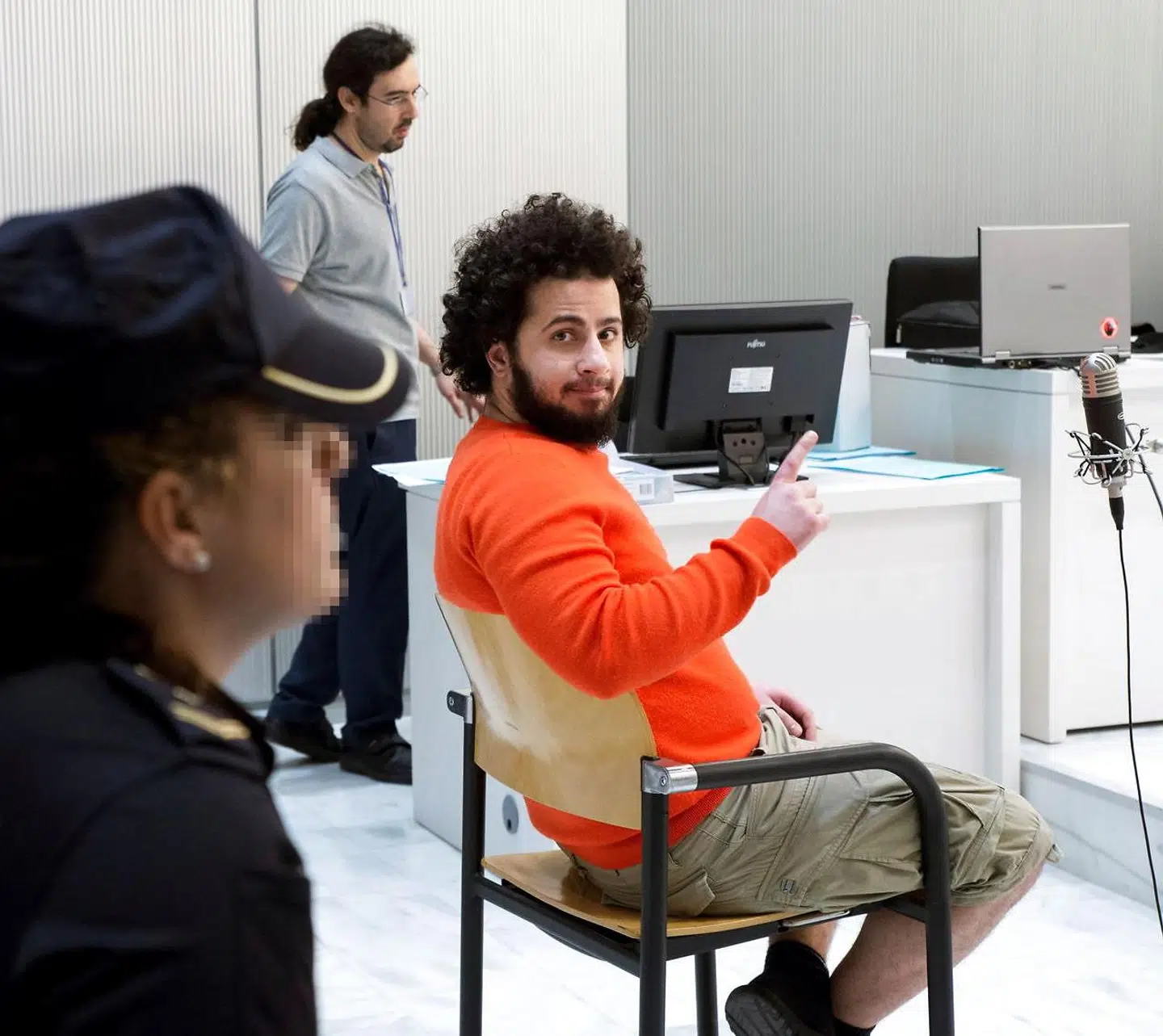 Ahmed Samsam rækker, iført orange trøje og shorts i retslokalet i Madrid, en finger i vejret. En kendt gestus, som i en islamisk kontekst symboliserer tawheed, ideen om at der kun findes én Gud. Tawheed-fingeren er, ligesom det sorte flag, siden 2014 ofte blevet set en hyldestmarkering til Islamisk Stat, men er på samme tid en almindelig gestus blandt nogle muslimer.