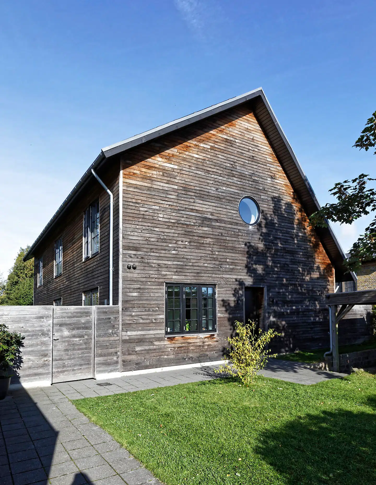 Det moderne hus i Vangede tiltrækker opmærksomhed og deler vandene. Facaden er beklædt med akacietræ, som ikke skal vedligeholdes. Det bliver gråt på solsiden og rødligt, hvor der er skygge.