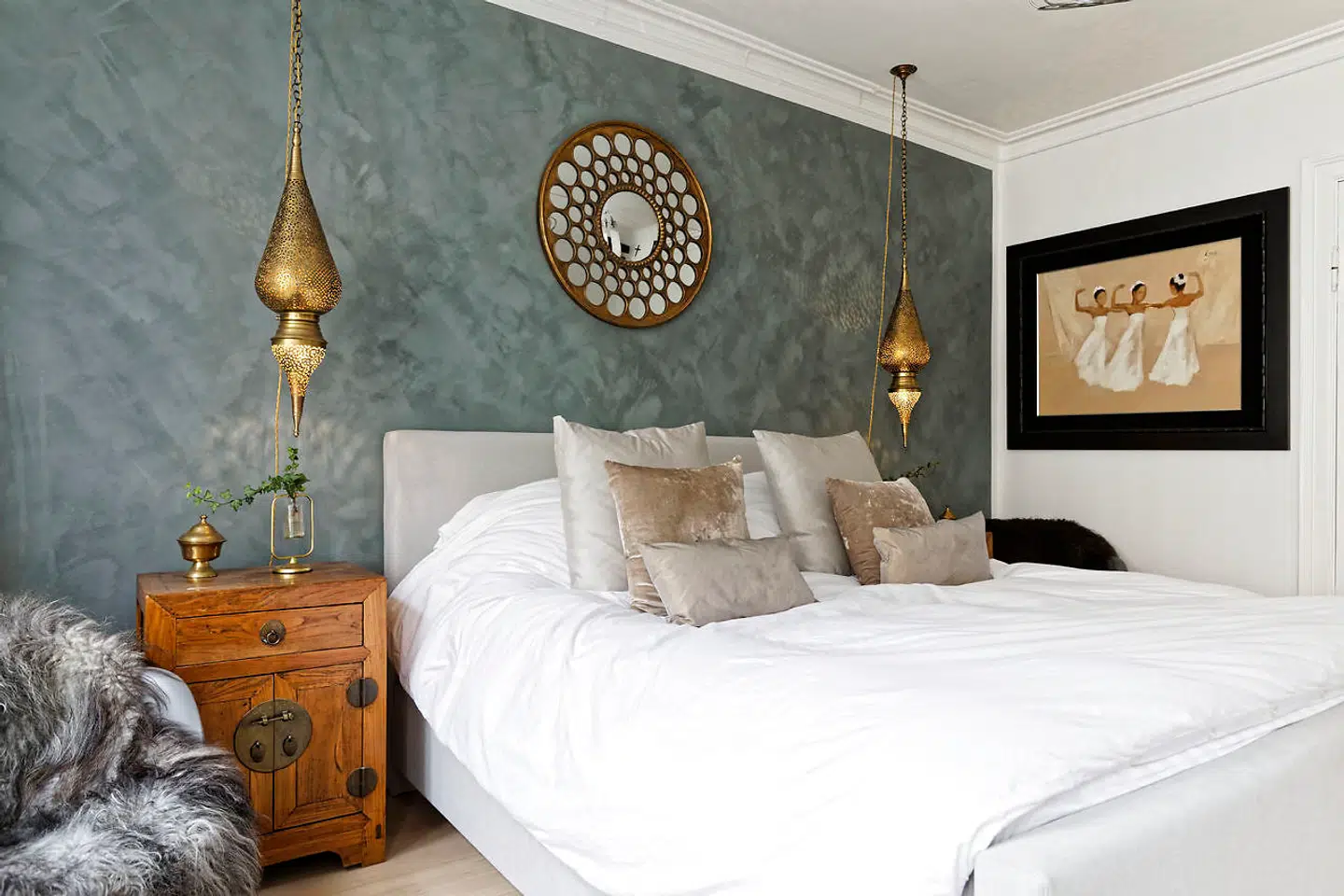 Bagvæggen af soveværelset i den inderste af de fire stuer er malet med grågrøn kalkmaling fra Farrow & Ball. Spejlet er indisk og lamperne marokkanske.