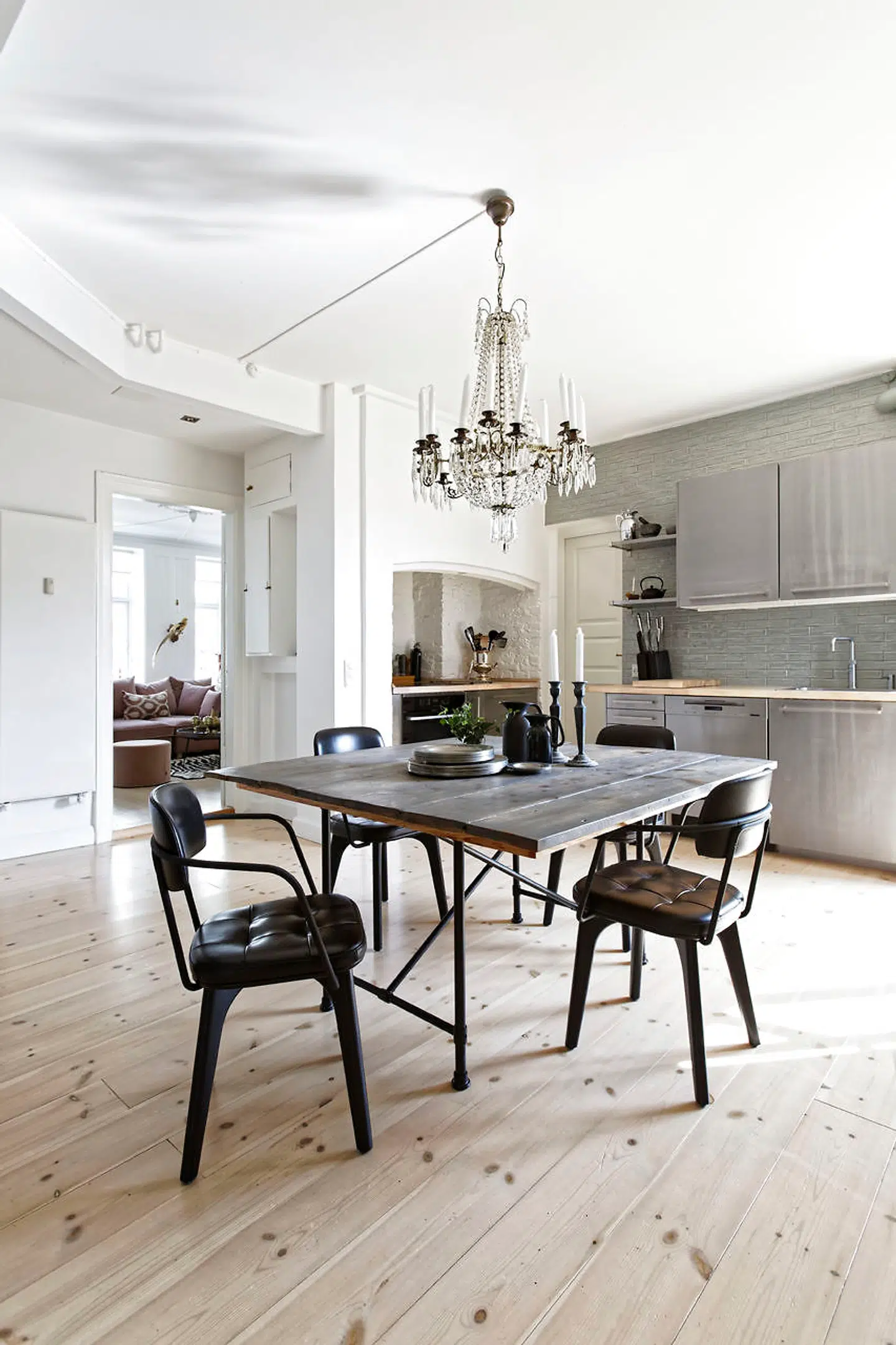 Det store køkken midt i lejligheden er blevet til ved at sammenlægge med entré og et spisekammer. Bordet af gamle gulvplanker, og stolene er Utility fra Stellarworks. Køkkenet af børstet stål er fra Ikea.