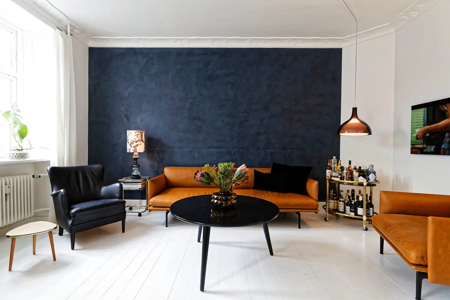 Væggen malet med koksgrå Kabe-maling danner baggrund for de nye Muuto-lædermøbler. Bord, barbord og lænestol er genbrug. Vasen var oprindeligt en lampe.