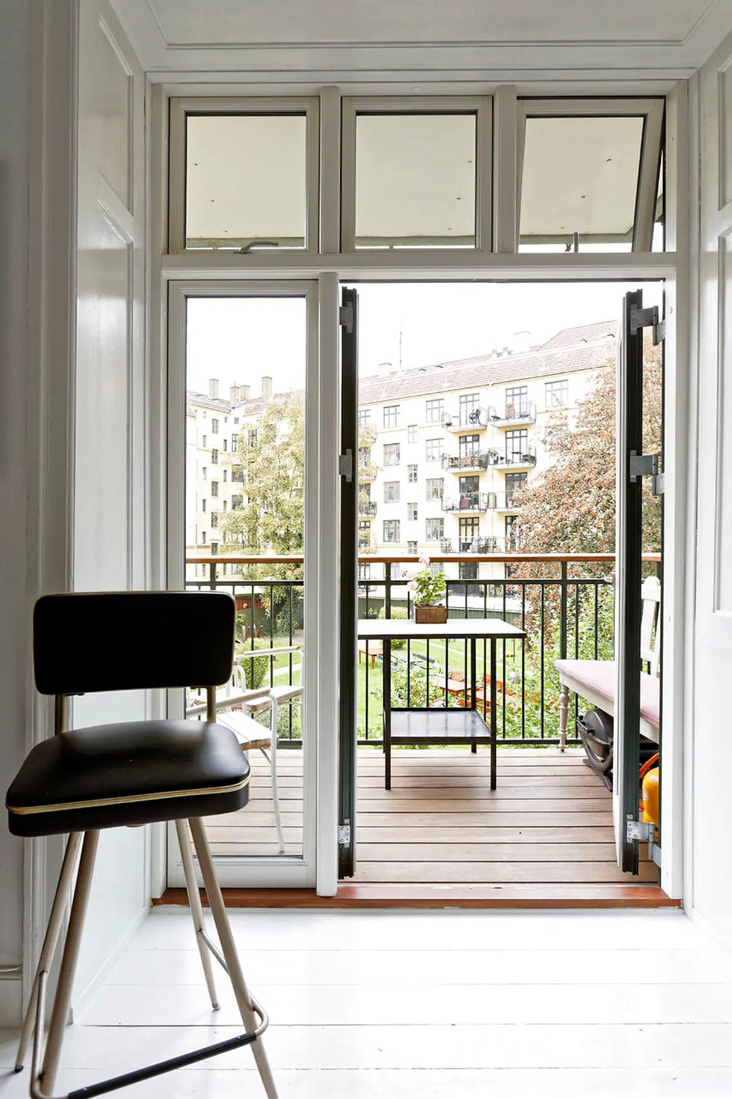 Fra køkken-alrummet er der adgang til den ene af lejlighedens to altaner med bænk og et gammelt gasbord. Den højbenede barstol fra 50erne er fra DBA.