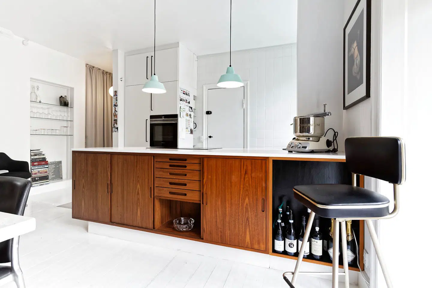 IKEA-køkken med corian-plade er bygget sammen med en 50er-skænk af teak. Forlængelsen giver plads til vinflasker. De mintgrønne lamper er fra Made By Hand.