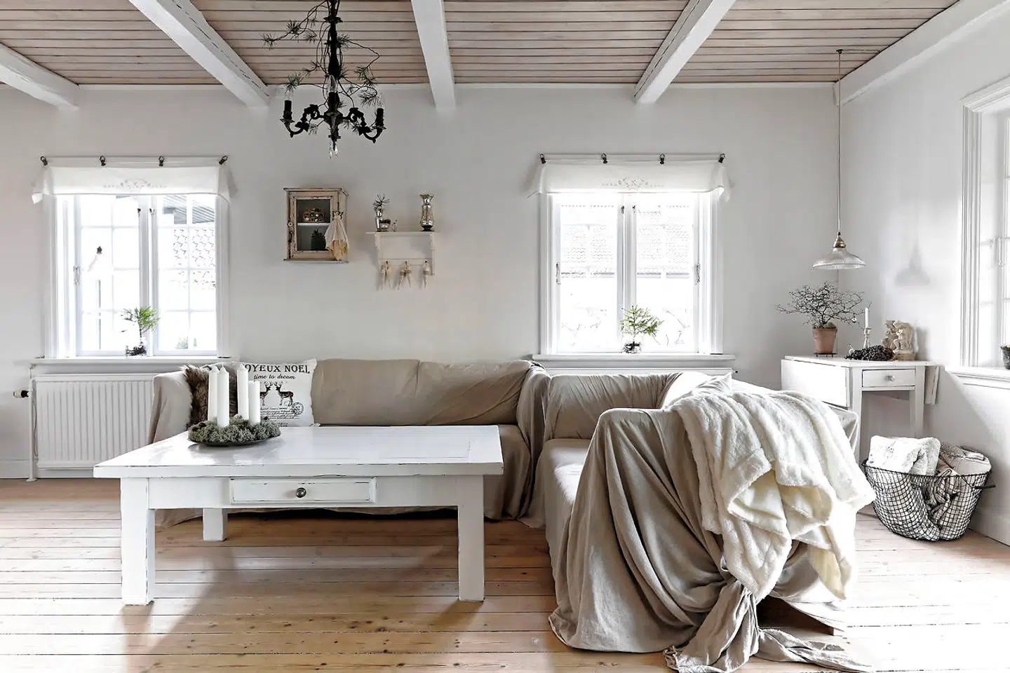 Lyse farver og hørstoffer får følgeskab af fattigmandssølv og materialer fra naturen til adventskrans med lav fra familiens sommerhushave på Bornholm. Julepuden er fra H&M.