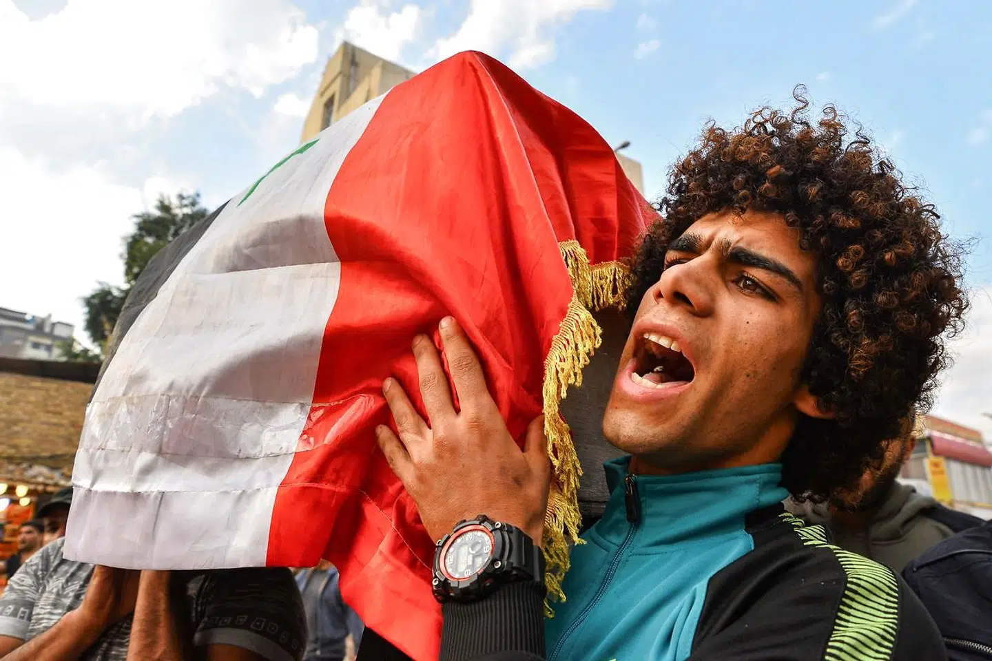 En sørgende demonstrant råber slagord, imens han bærer på en kiste iklædt det irakiske flag, som indeholder en chauffør dræbt i en kamp mellem demonstranter og sikkerhedsstyrker i Baghdad.