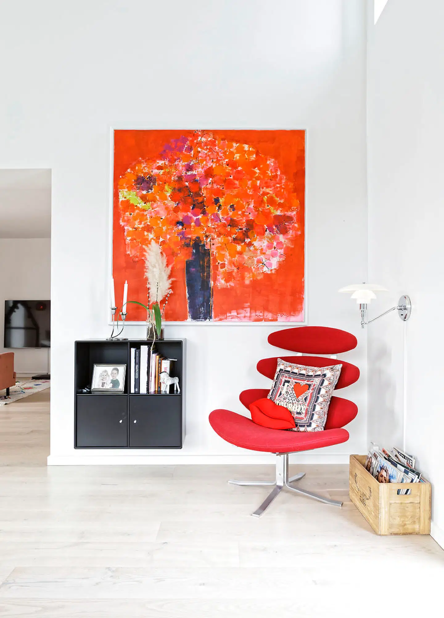 Den røde Corona-stol designet af Poul M. Volther står i et hjørne af stuen. Det orangerøde maleri er af Tove Andresen.