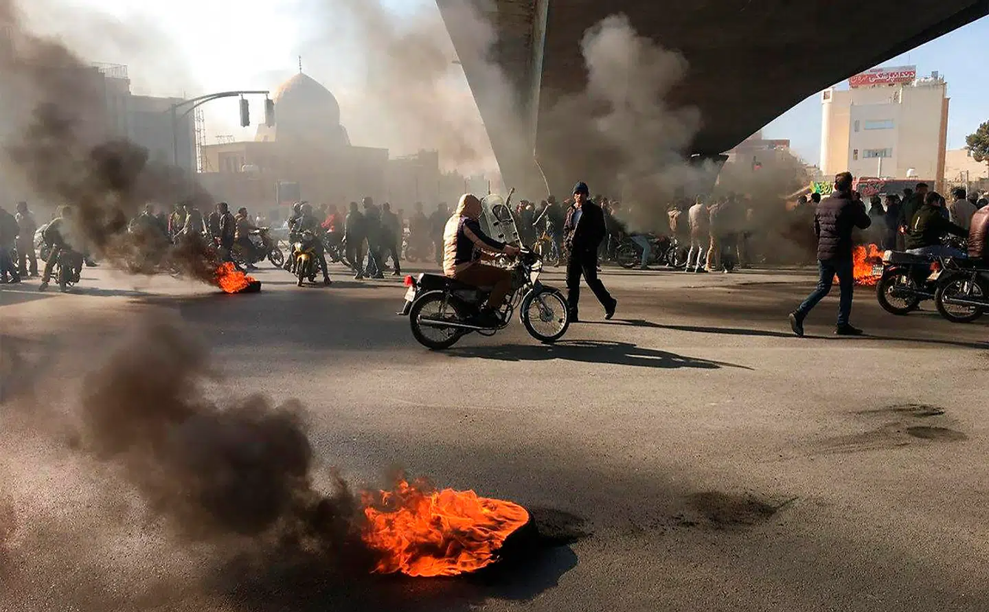Iranian protesters rally amid burning tires during a demonstration against an increase in gasoline prices, in the central city of Isfahan on November 16, 2019. - One person was killed and others injured in protests across Iran, hours after a surprise decision to increase petrol prices by 50 percent for the first 60 litres and 300 percent for anything above that each month, and impose rationing. Authorities said the move was aimed at helping needy citizens, and expected to generate 300 trillion rials ($2.55 billion) per annum. (Photo by - / AFP)