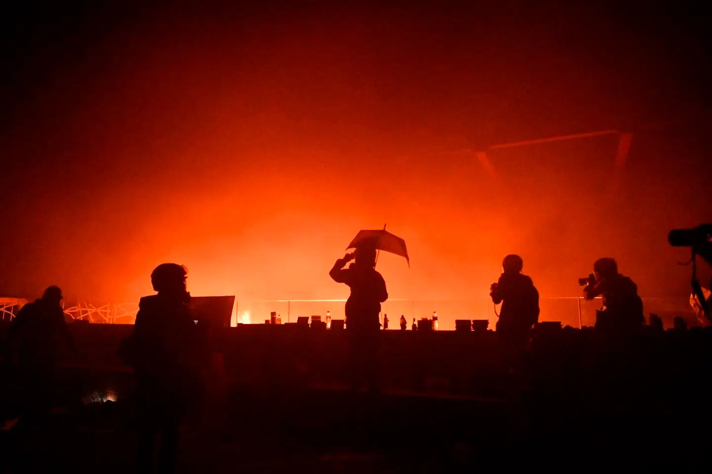 Demonstranter og journalister ser ned på den ild, der er ved hovedindgangen til det barikeret Hong Kong Polytechnic University. En større brand har, ifølge AFP, brændt gennem dele af mandagen efter at demonstranter kastede brandbare væsker på politiet for at holde dem ude af campus.