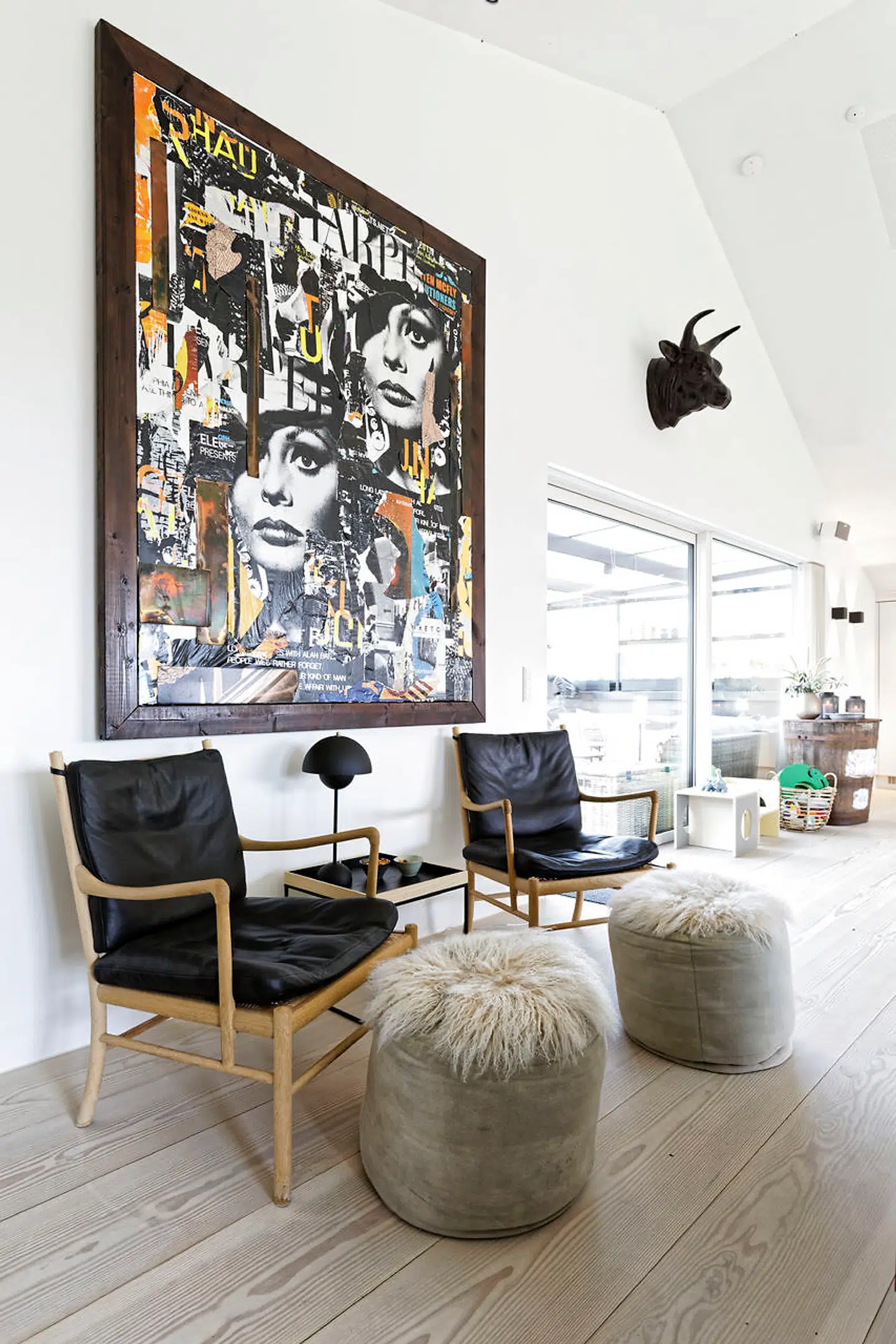 På samtalepladsen med to Ole Wanscher-stole tænker parret store tanker om byggeri og rejser. Collagekunsten er af bysbarnet Bjørn Agertved.