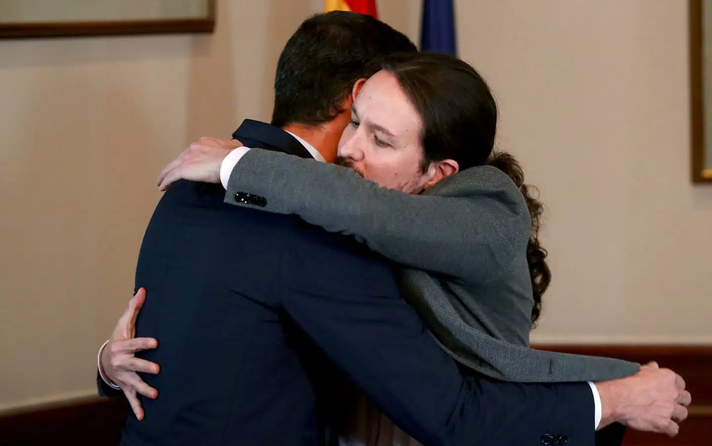Podemos-lederen Pablo Iglesias lukker øjnene, mens han giver en sydeuropæisk mandfolkekrammer til en tydeligvis overrasket premierminister Pedro Sánchez.